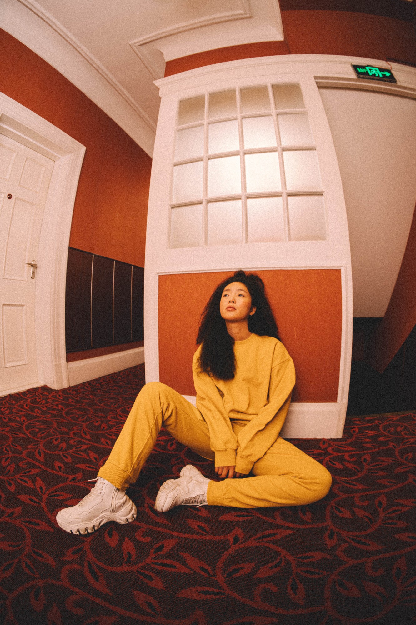 a model sits in a hotel corridor wearing UN GARCON CHARMANT AW22