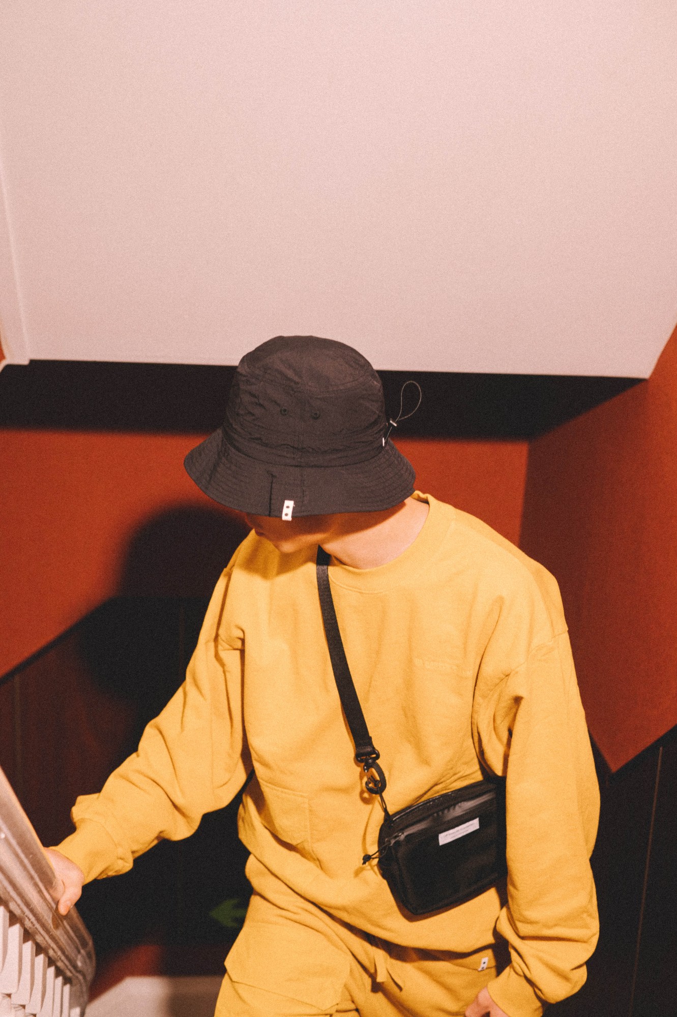 a model stands in a hotel corridor wearing UN GARCON CHARMANT AW22