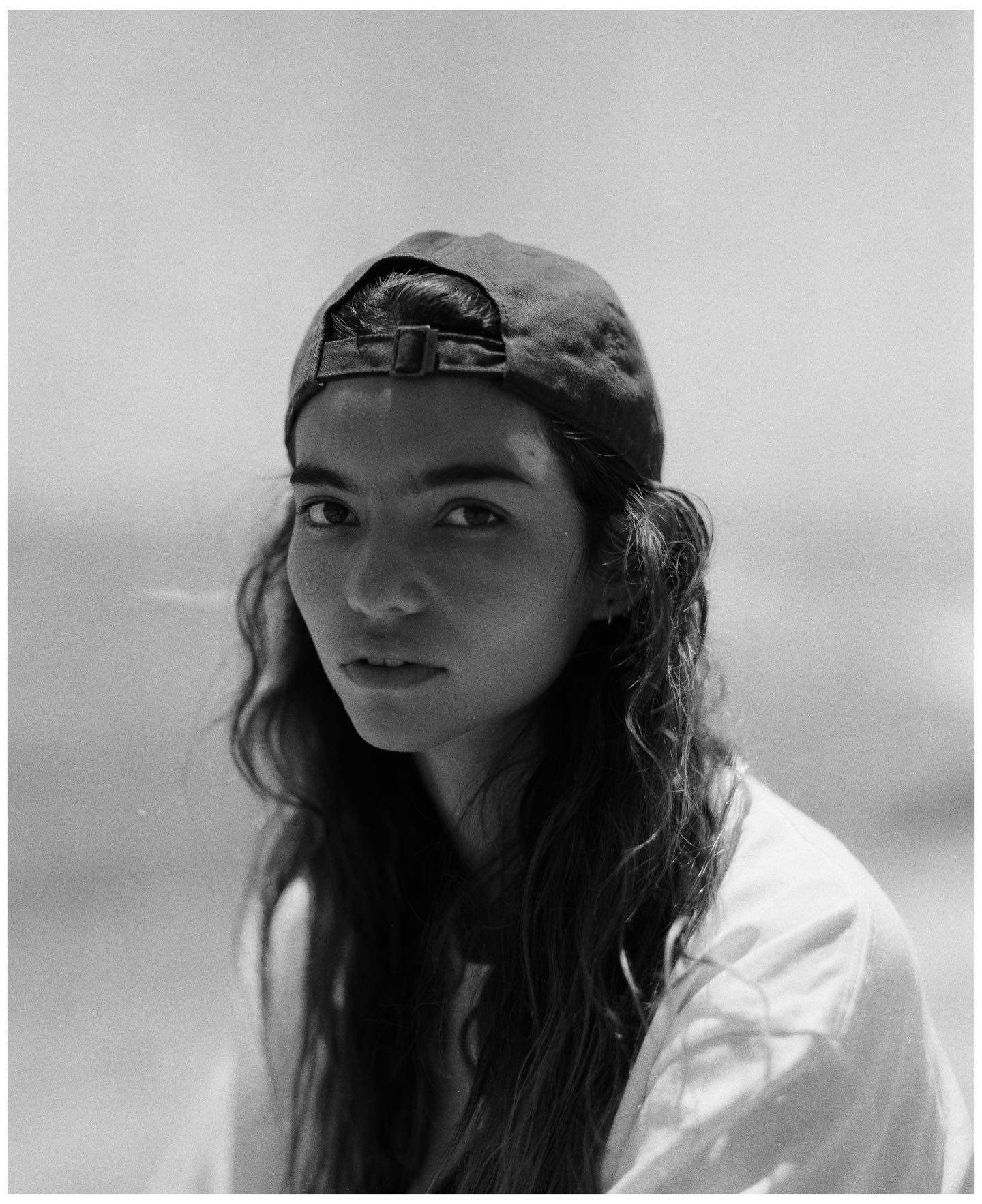 Portrait of a girl wearing a backwards grey cap and a white t-shirt.