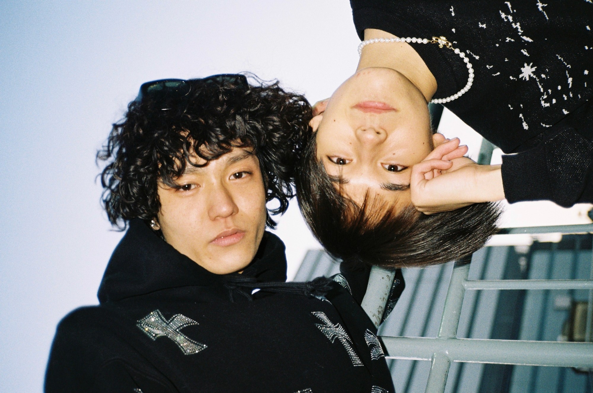 Two friends, one upside down, looking serious in front of a glass building