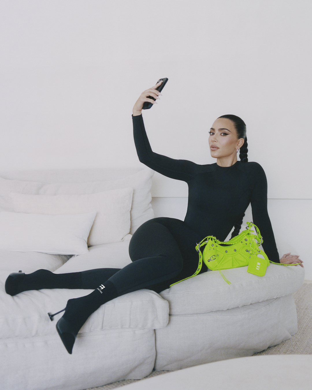 Kim Kardashian posing with Balenciaga's Le Cagole bag in neon green in her home