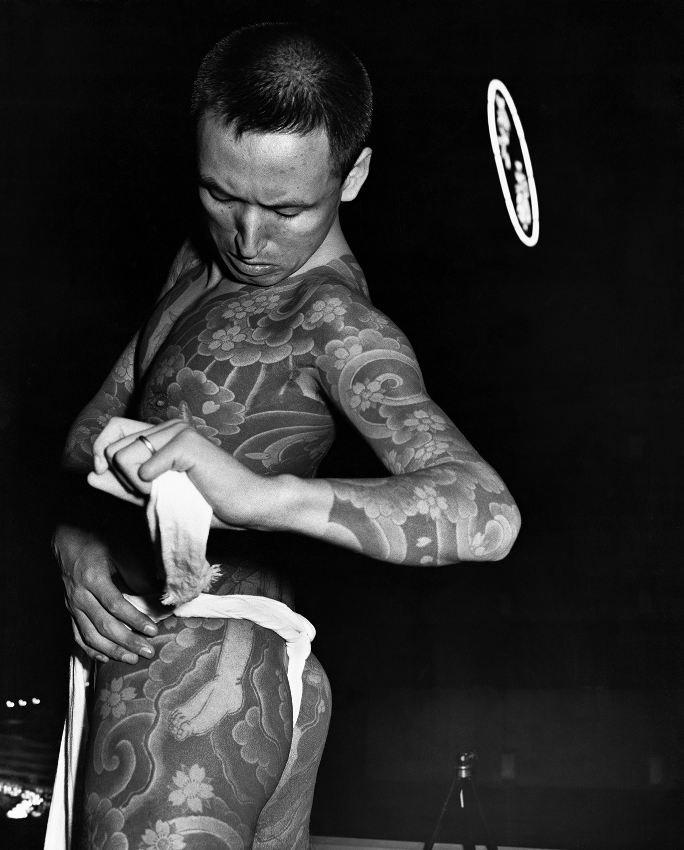 a tattooed nightclub performer tying a towel around his body in tokyo in the 70s by seiji kurata