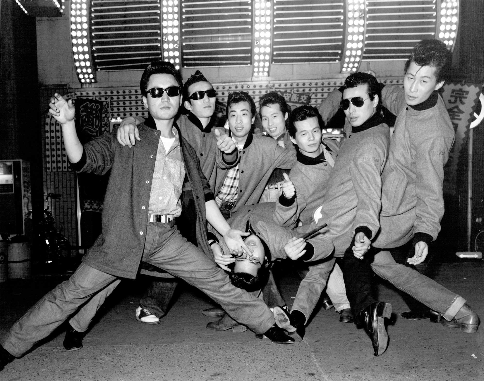 a group of young japanese men in matching coats and sunglasses posing outside a club in tokyo by seiji kurata