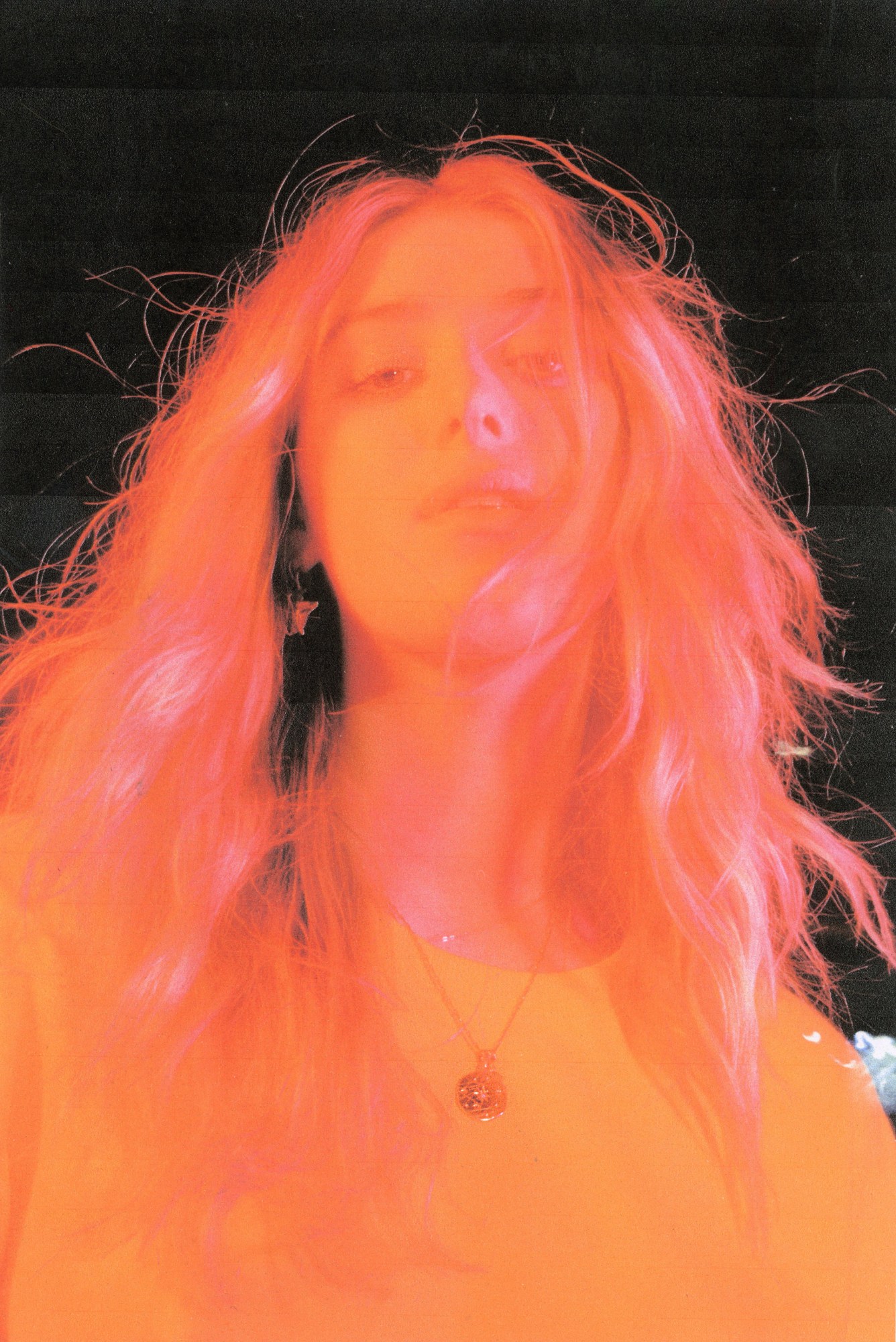 a pink and orange tinged portrait of honor swinton byrne looking down at the camera