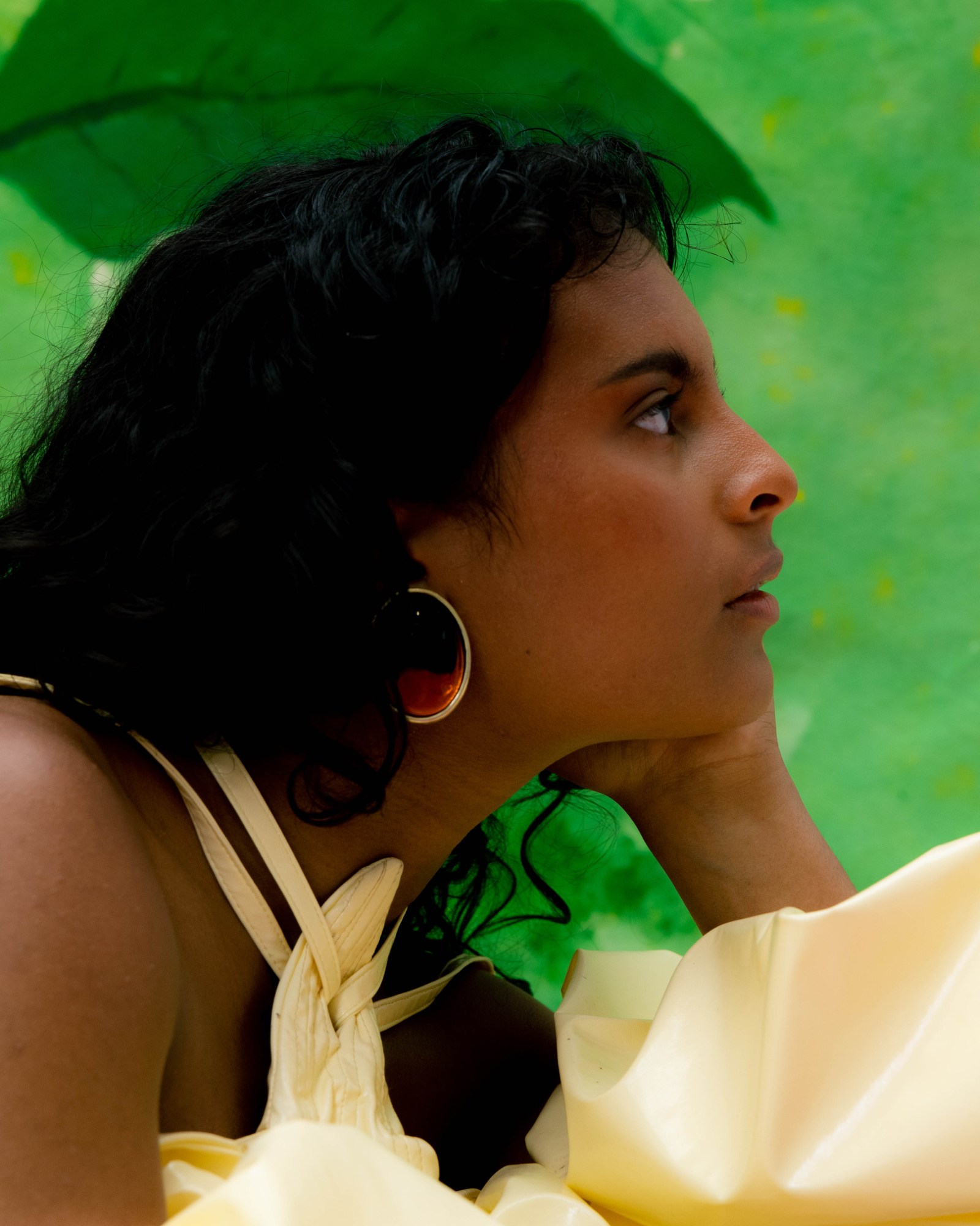 a side profile portrait of a model in front of a green painted backdrop