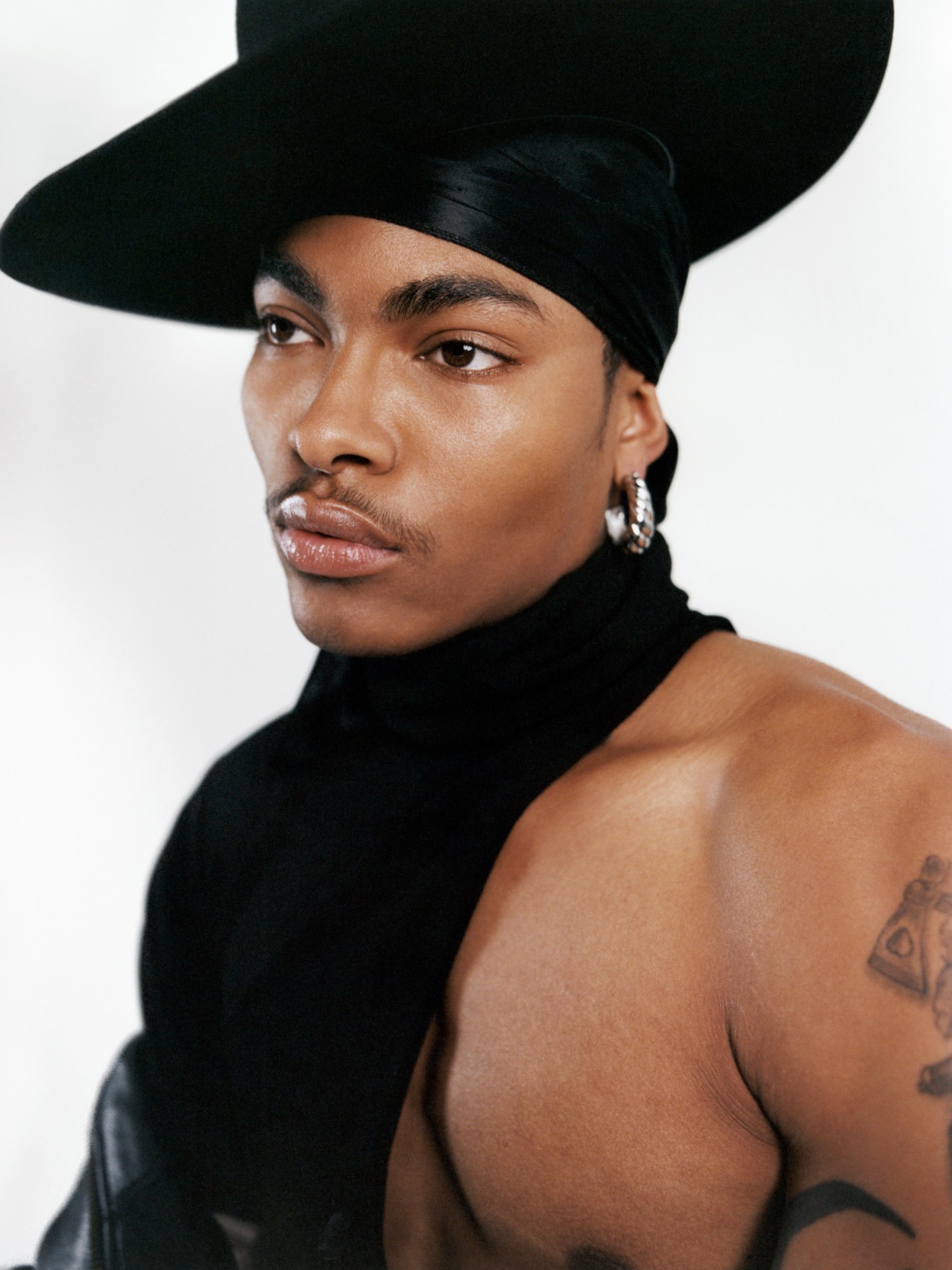 a man wearing a durag and a hat, with half his torso exposed