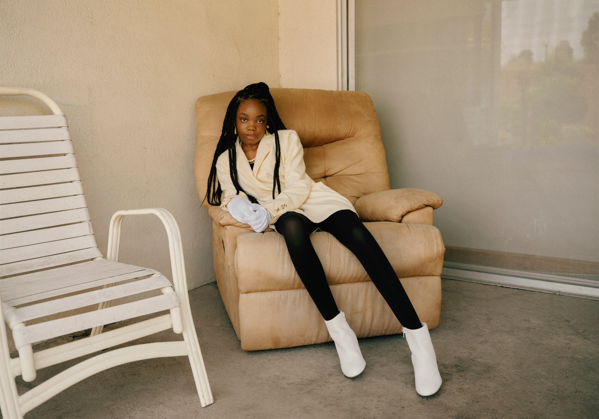 a young girl sits on a chair in smart clothing