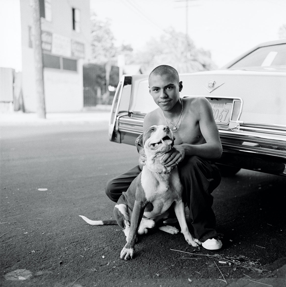 a man and his dog pose in the street in east la