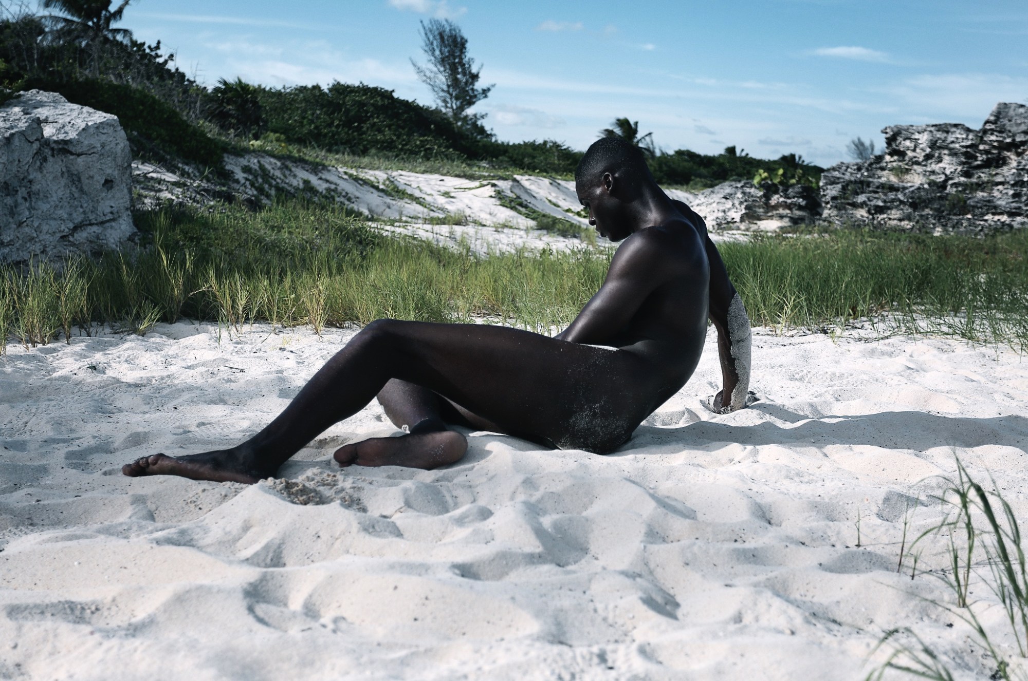 a naked man lies on the sand