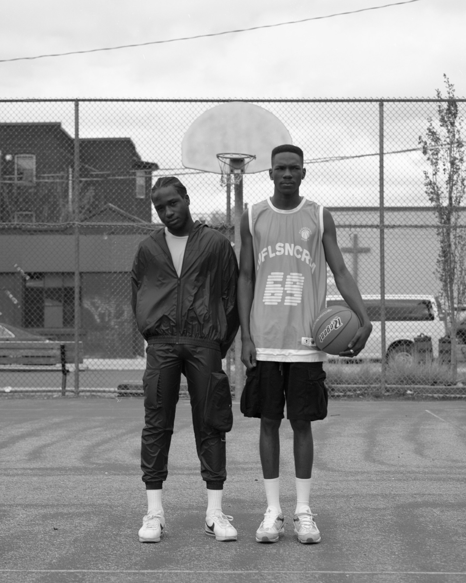 two models stand on a basketball court facing the camera, the model on the right with a ball in his hand