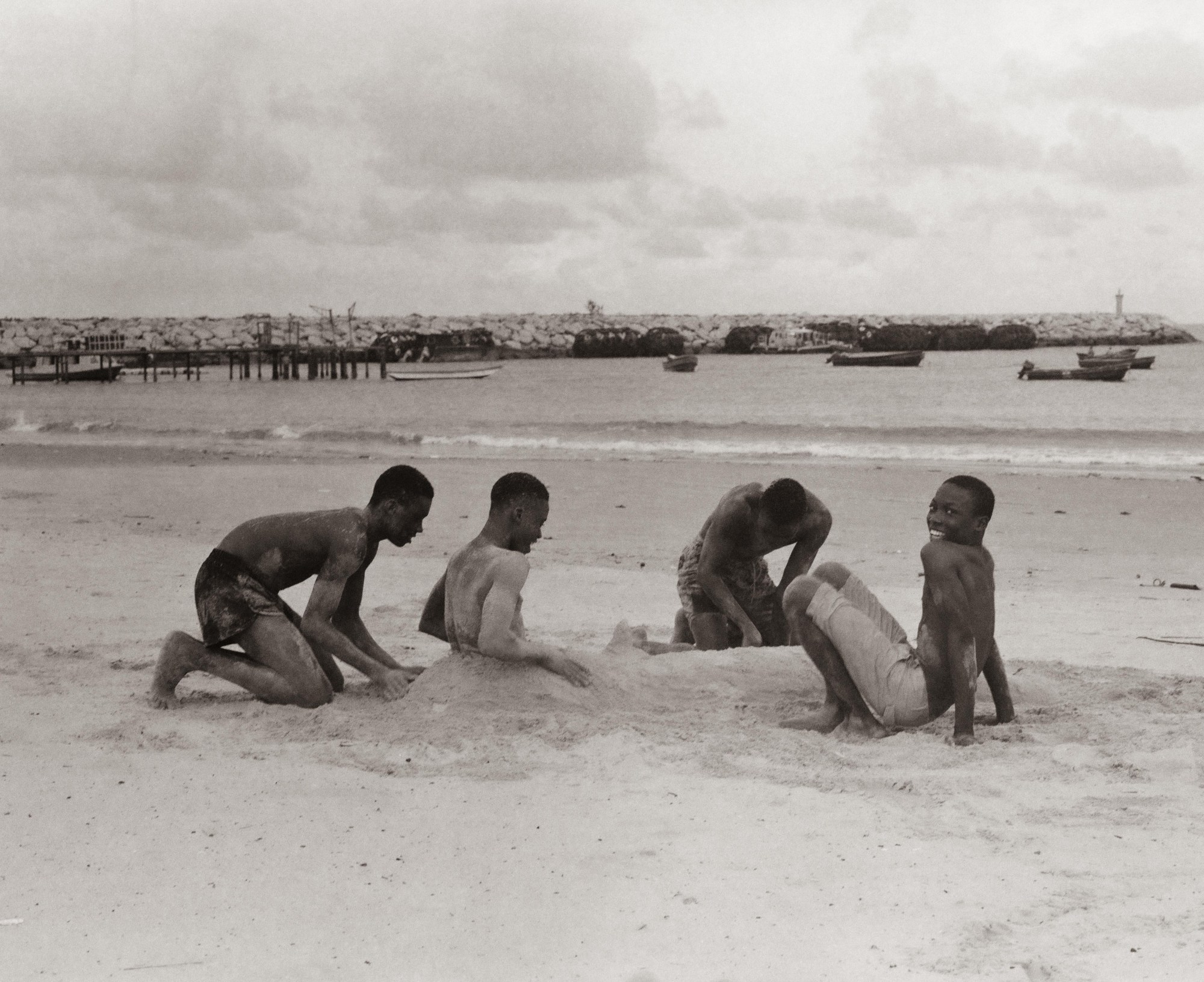 four models play on the beach in the sand in a sepia tone image