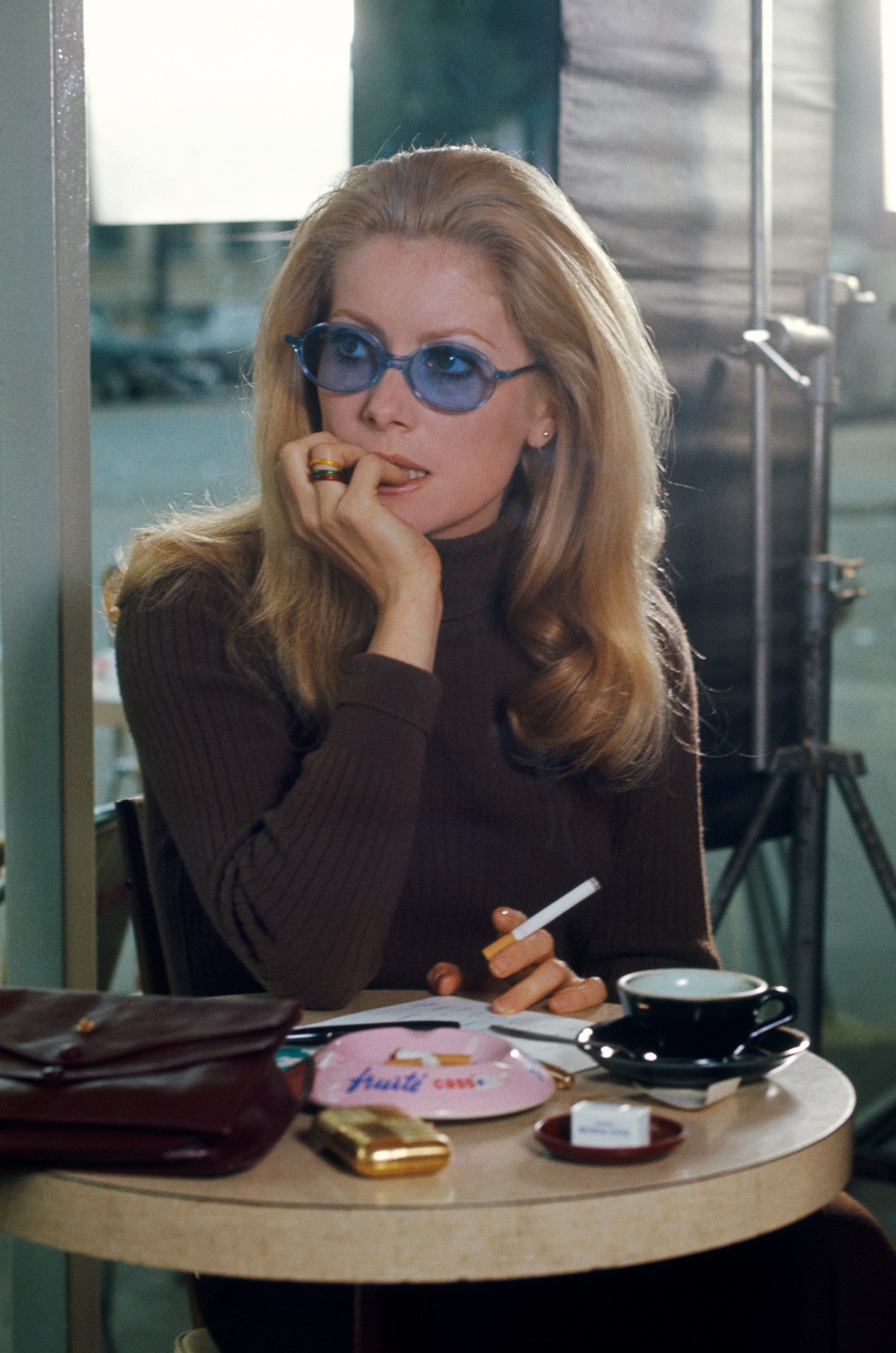 catherine deneuve wearing blue tinted glasses and smoking a cigarette in manon 70