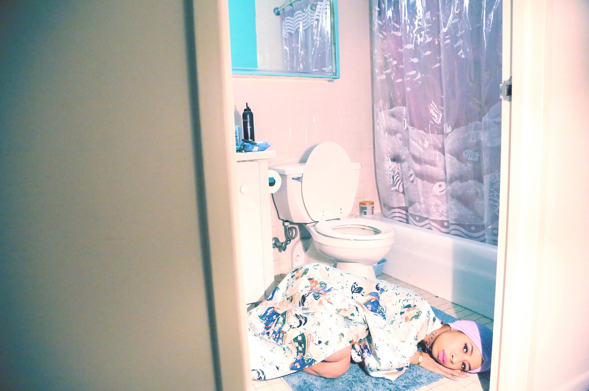 a self-portrait of kia labeija lying on the bathroom floor