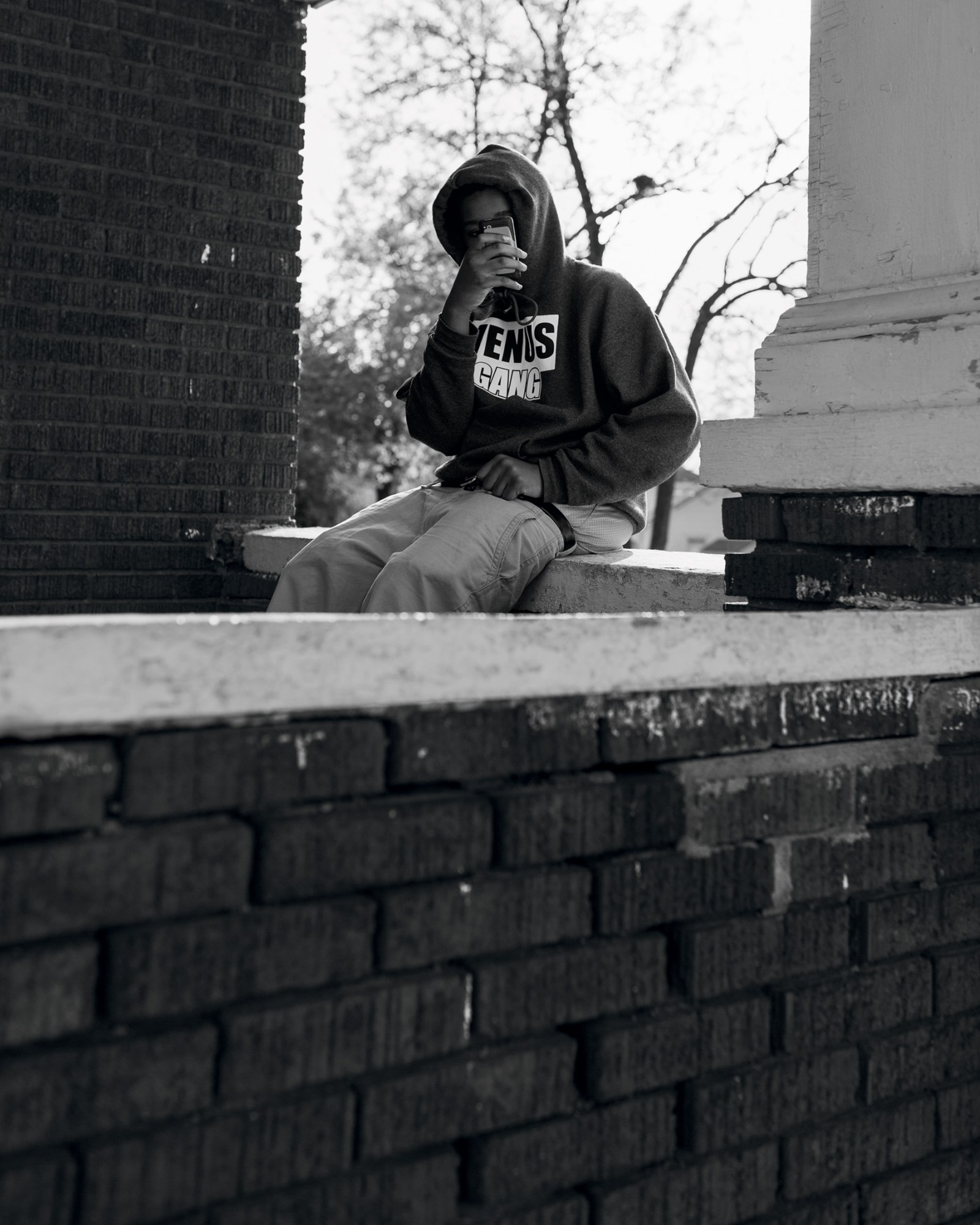 A man in a hoodie sitting on a front porch