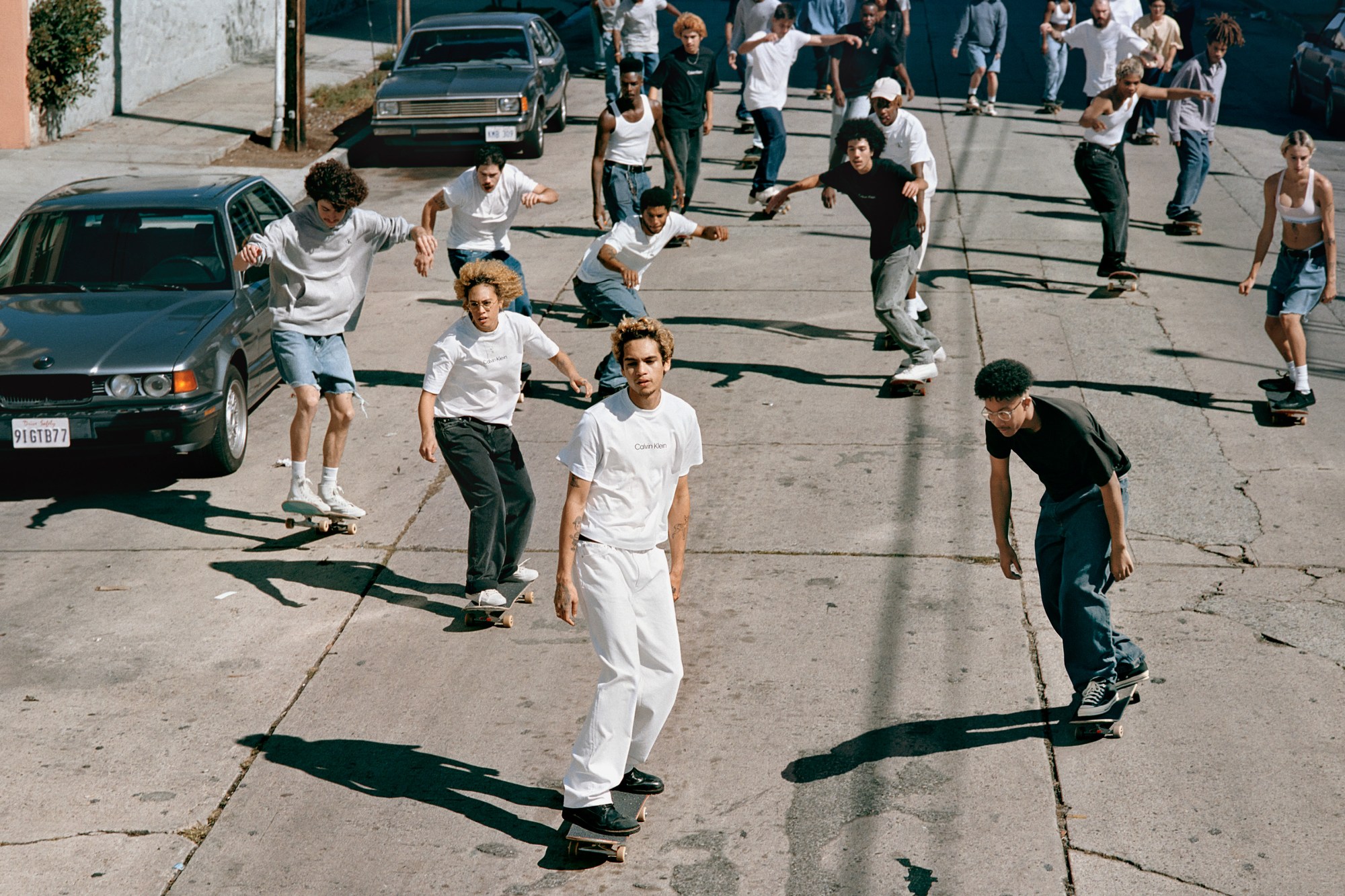 Dominic Fike and a group of models wearing Calvin Klein and skating down the street.