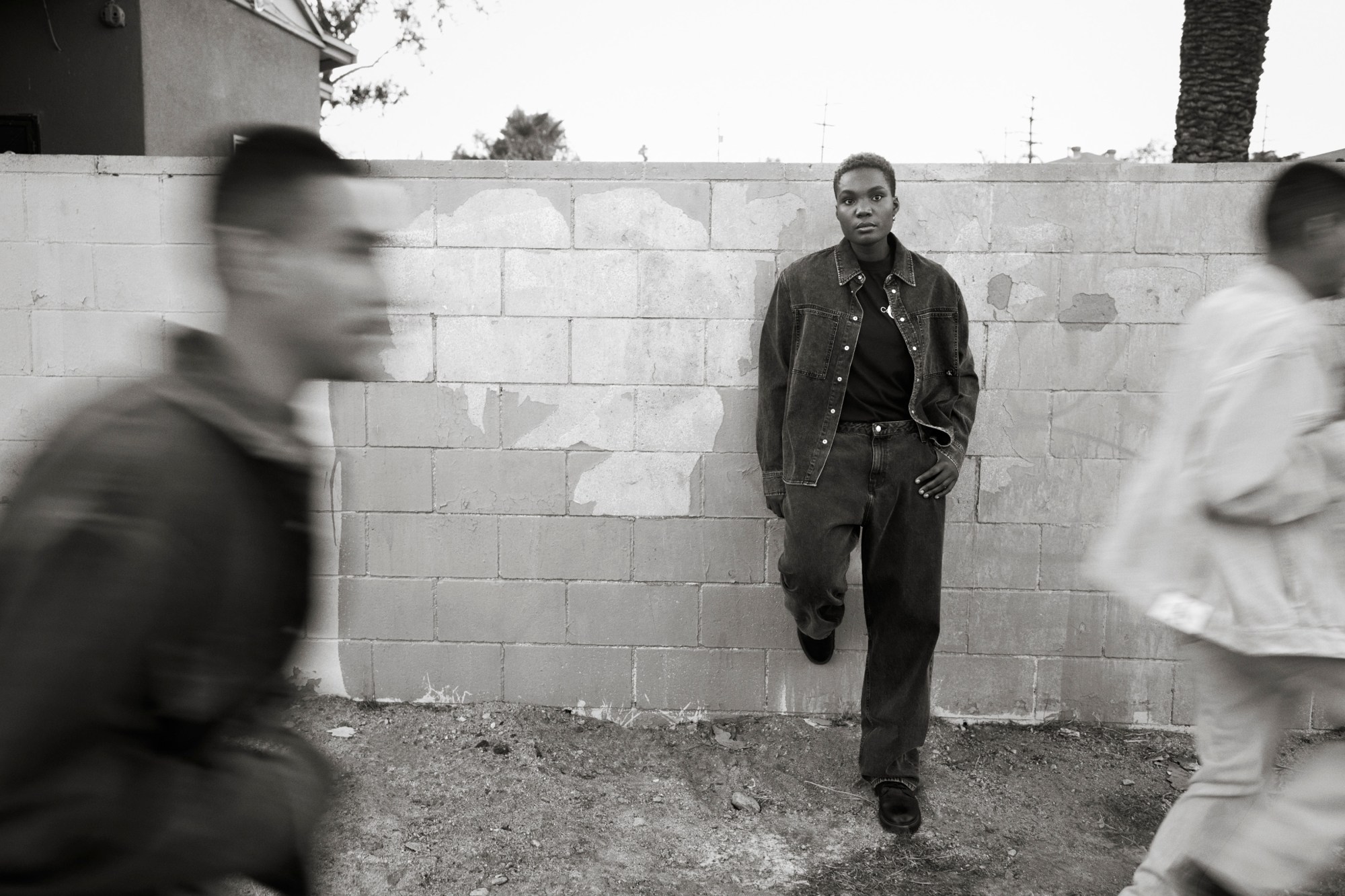 Arlo Parks wearing Calvin Klein standing against a wall.