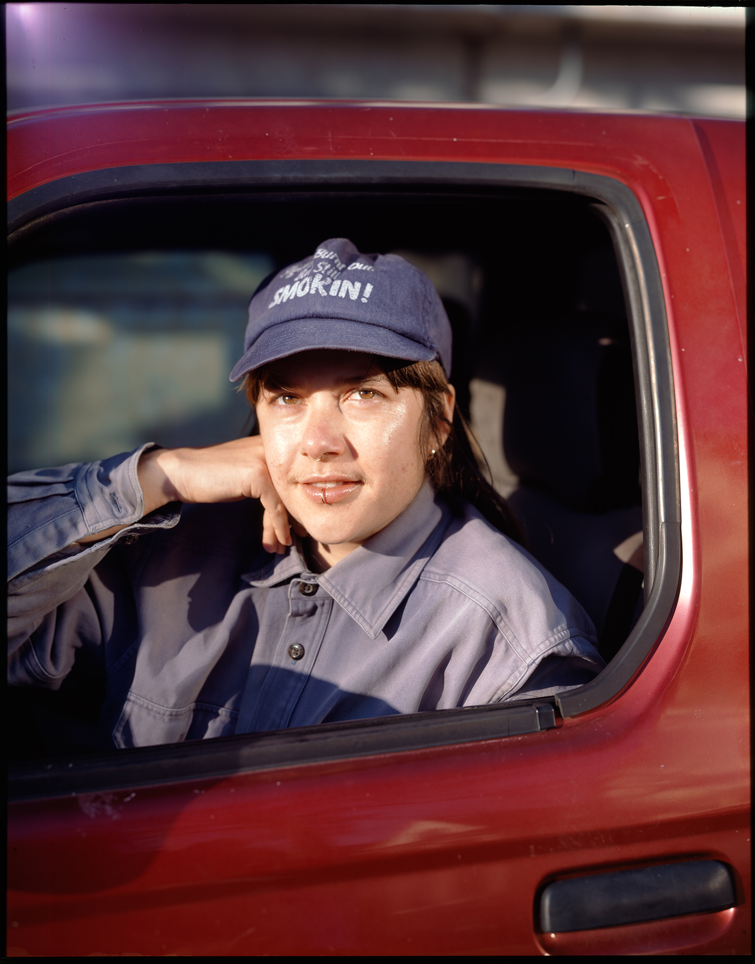 a portrait of cherry sitting in a red truck by ian lewandowski