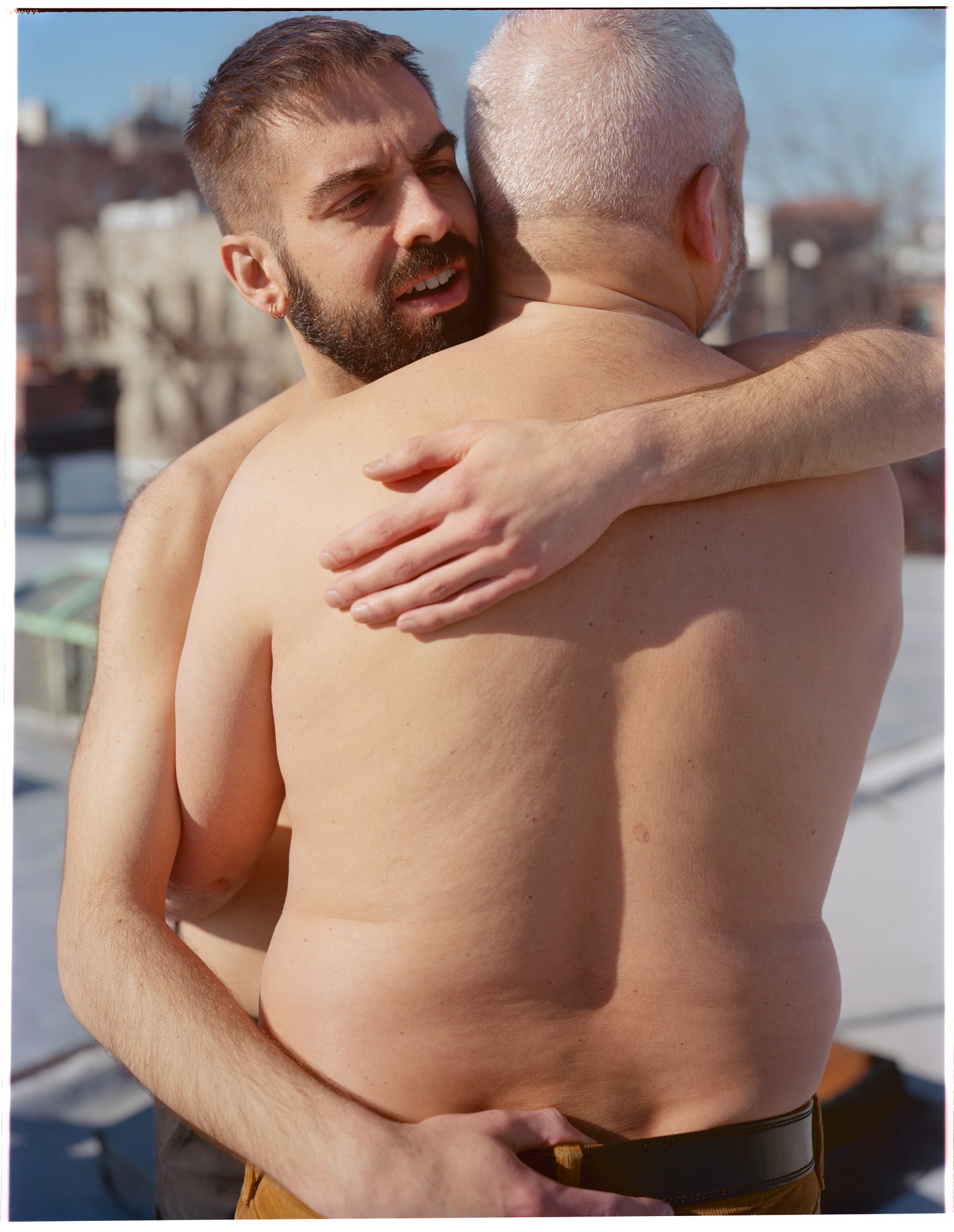 a portrait of two shirtless men hugging on a new york rooftop by ian lewandowski