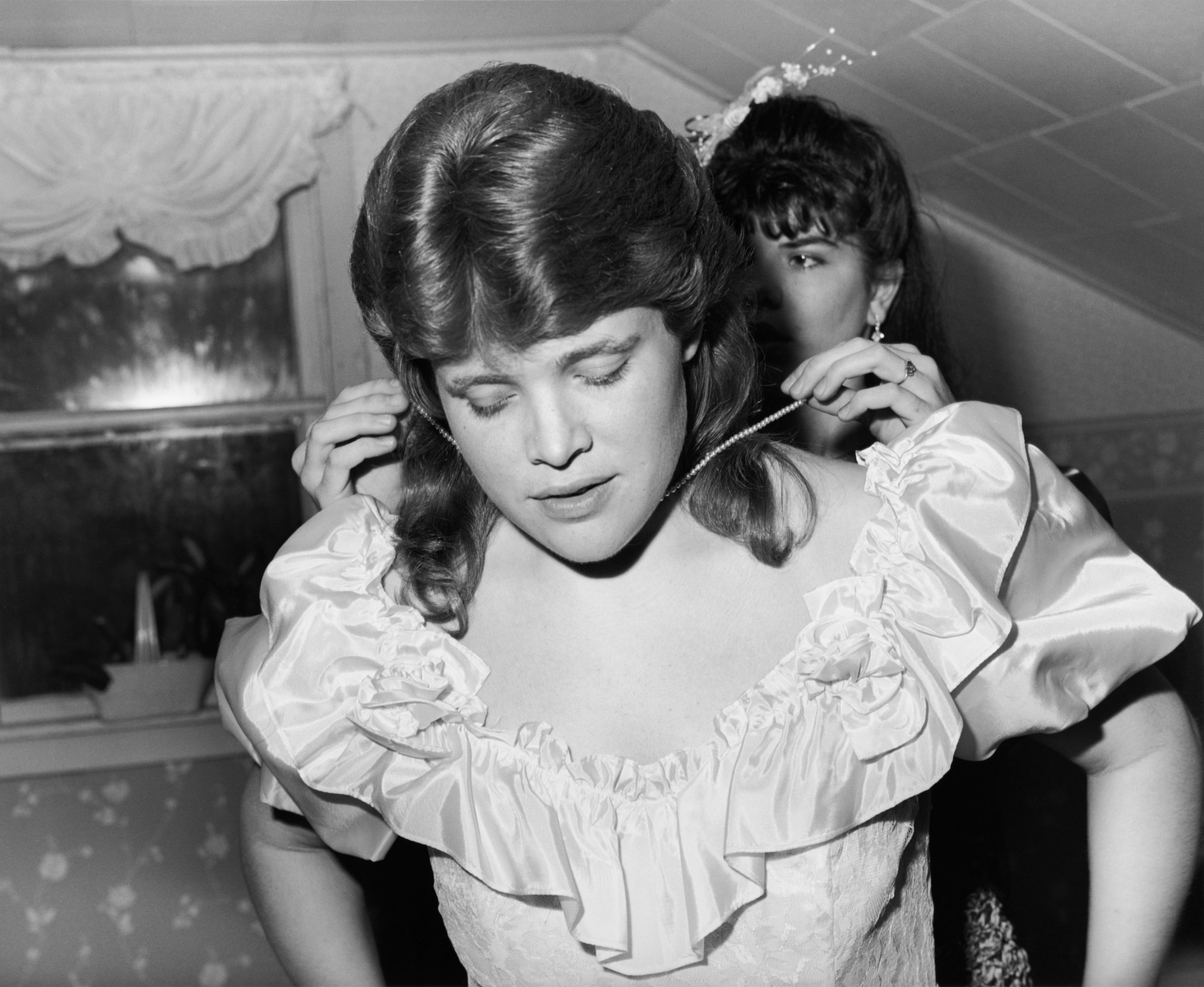 two girls putting on a necklace and getting ready for prom in the 80s by ken graves and eva lipman