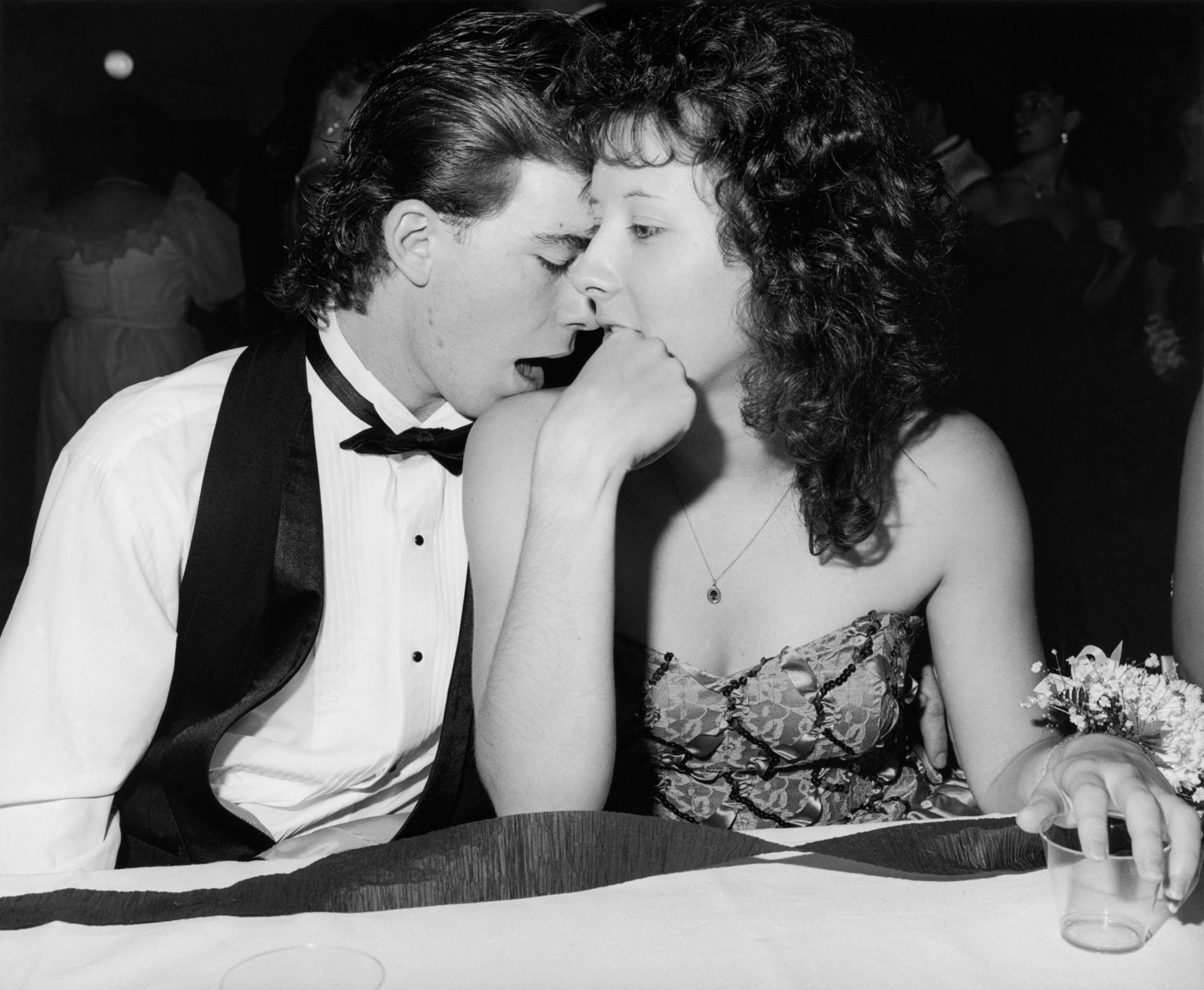 a couple sitting at a table and embracing at their high school prom by ken graves and eva lipman