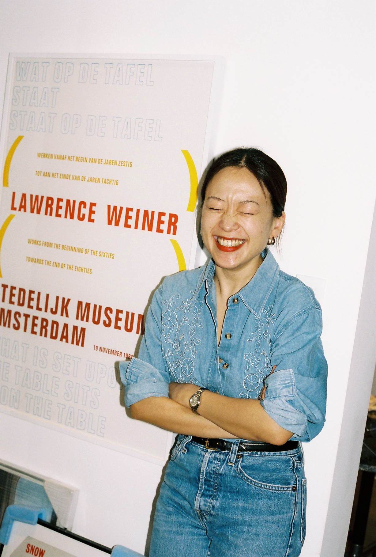 a smiling woman wears read lipstick and double denim