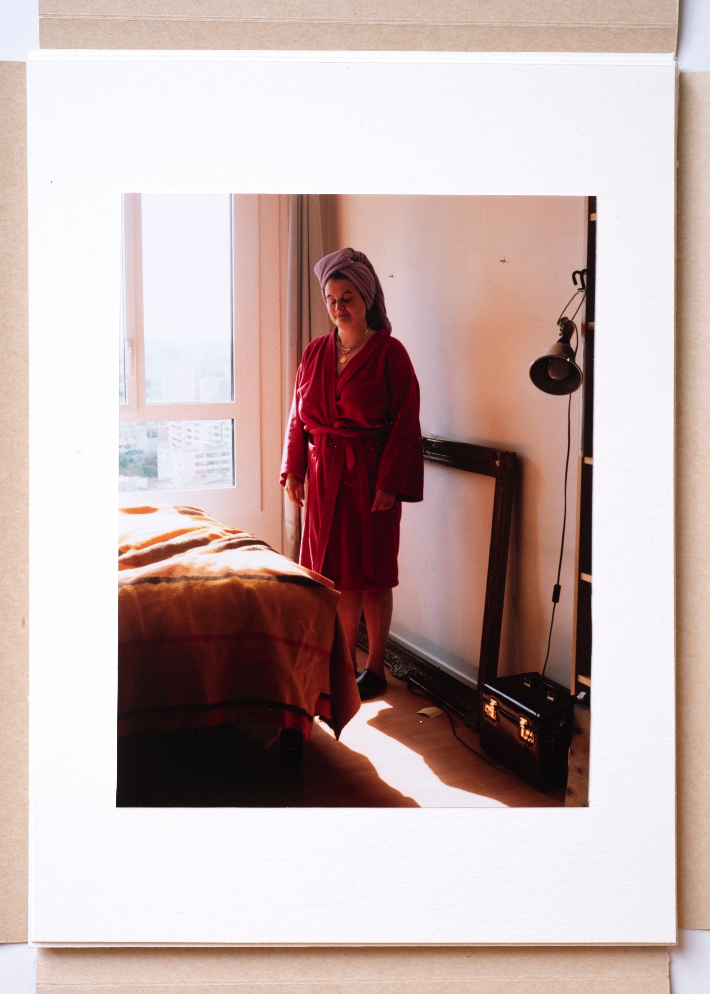 a woman in a bedroom wearing a towel robe and wrap around her head