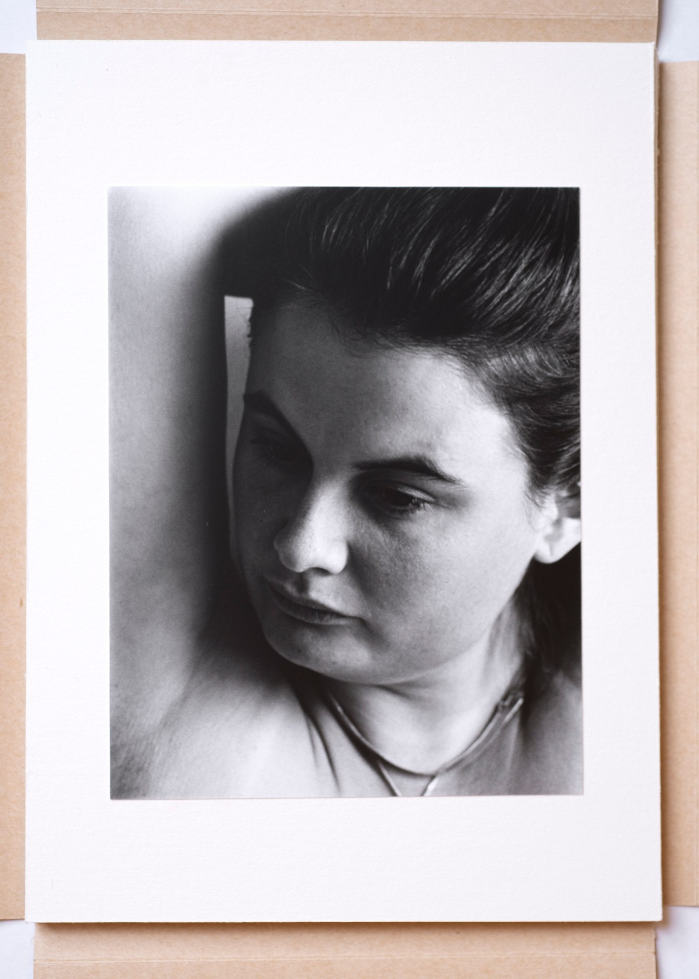 a black ad white portrait of a woman with her hand above her head, looking out of frame