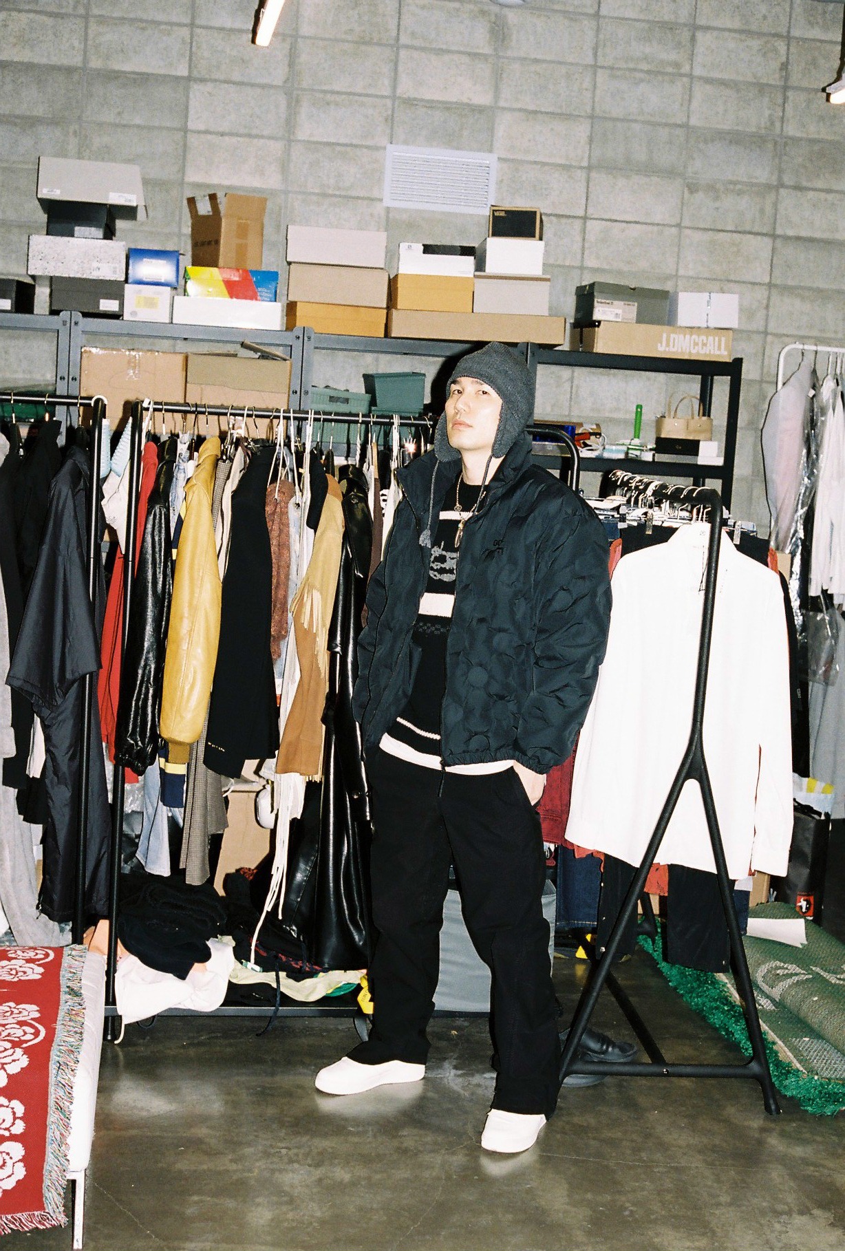 stylist fwanwook jung stands in front of some busy rails of clothing