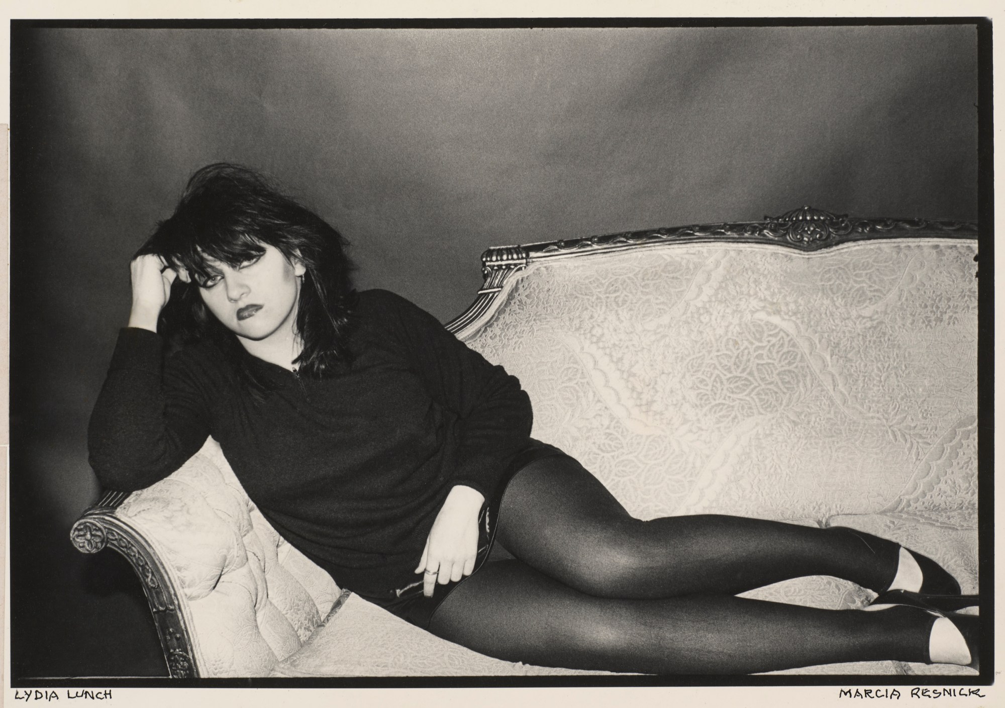 Photograph of Lydia Lunch lying on a chase lounge photographed by Marcia Resnick.