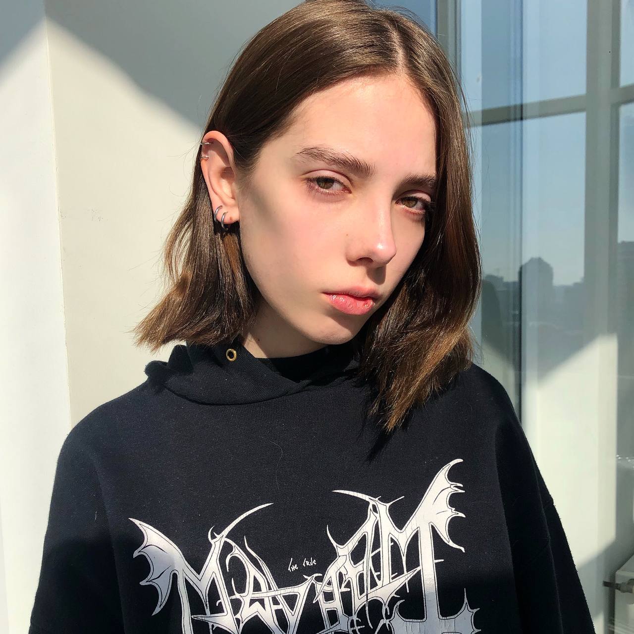 a photo of a model in a metal hoodie, standing in the sunlight