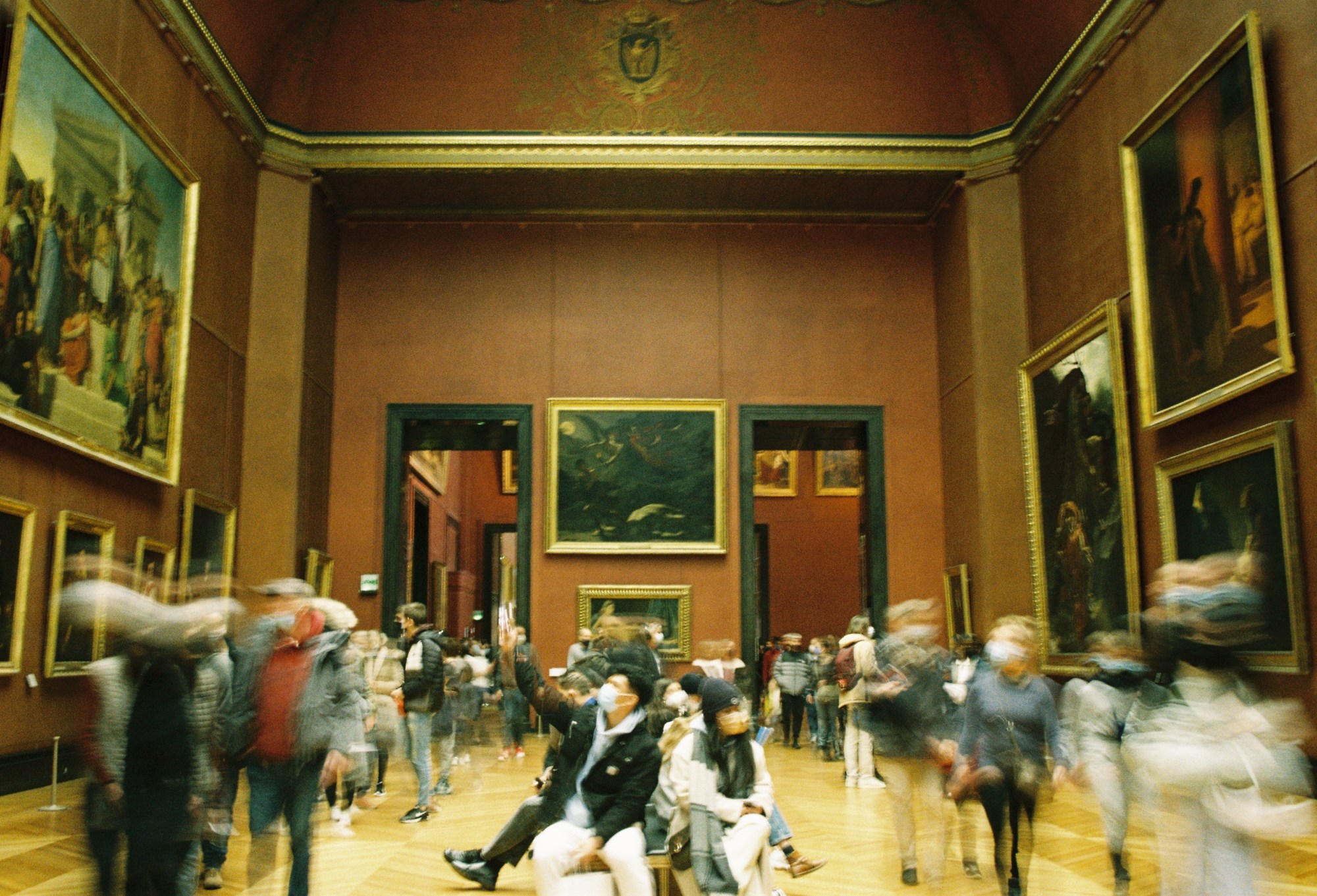 Photo of a gallery room in the Louvre while it's busy.