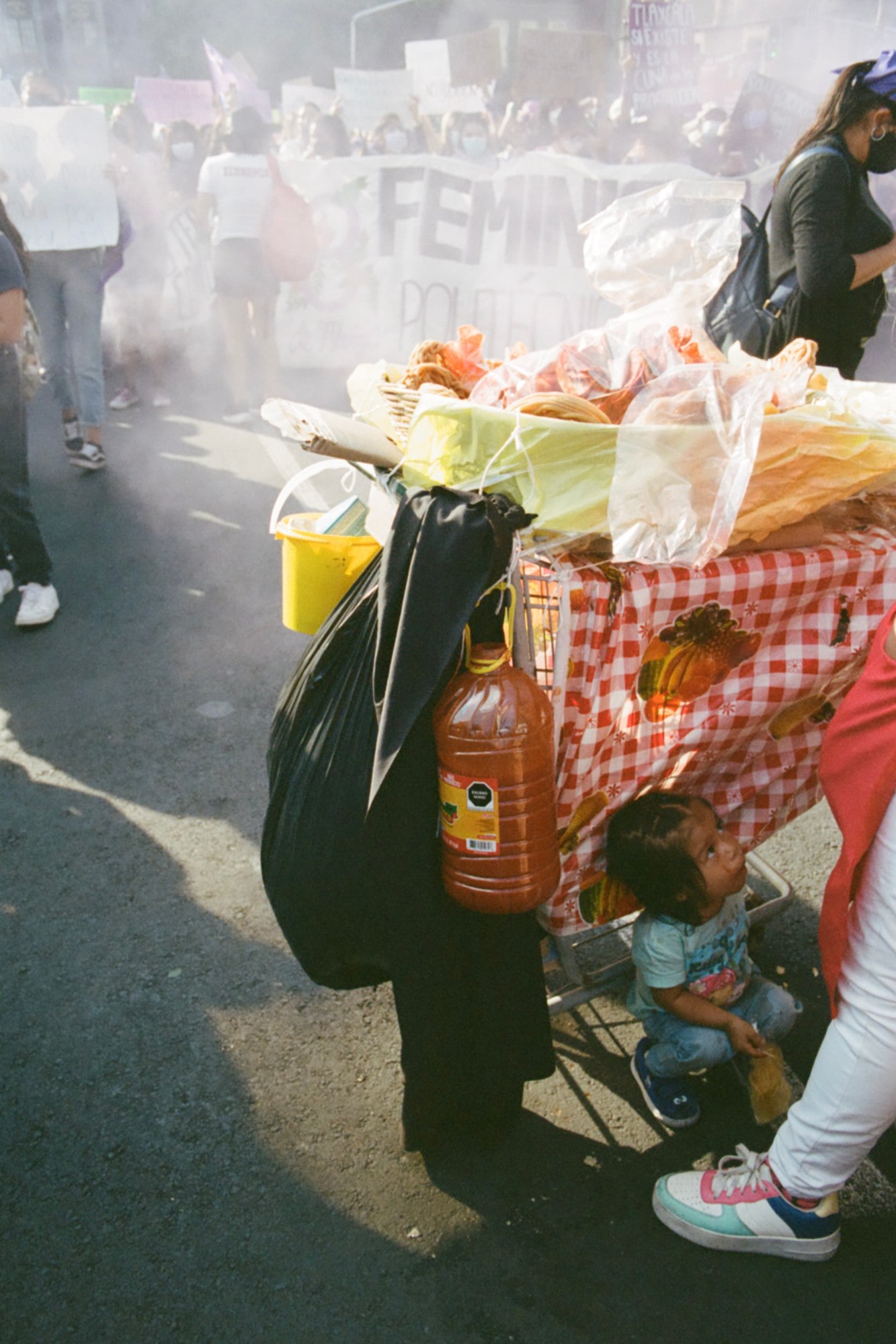 a child sitting under a fruit stand