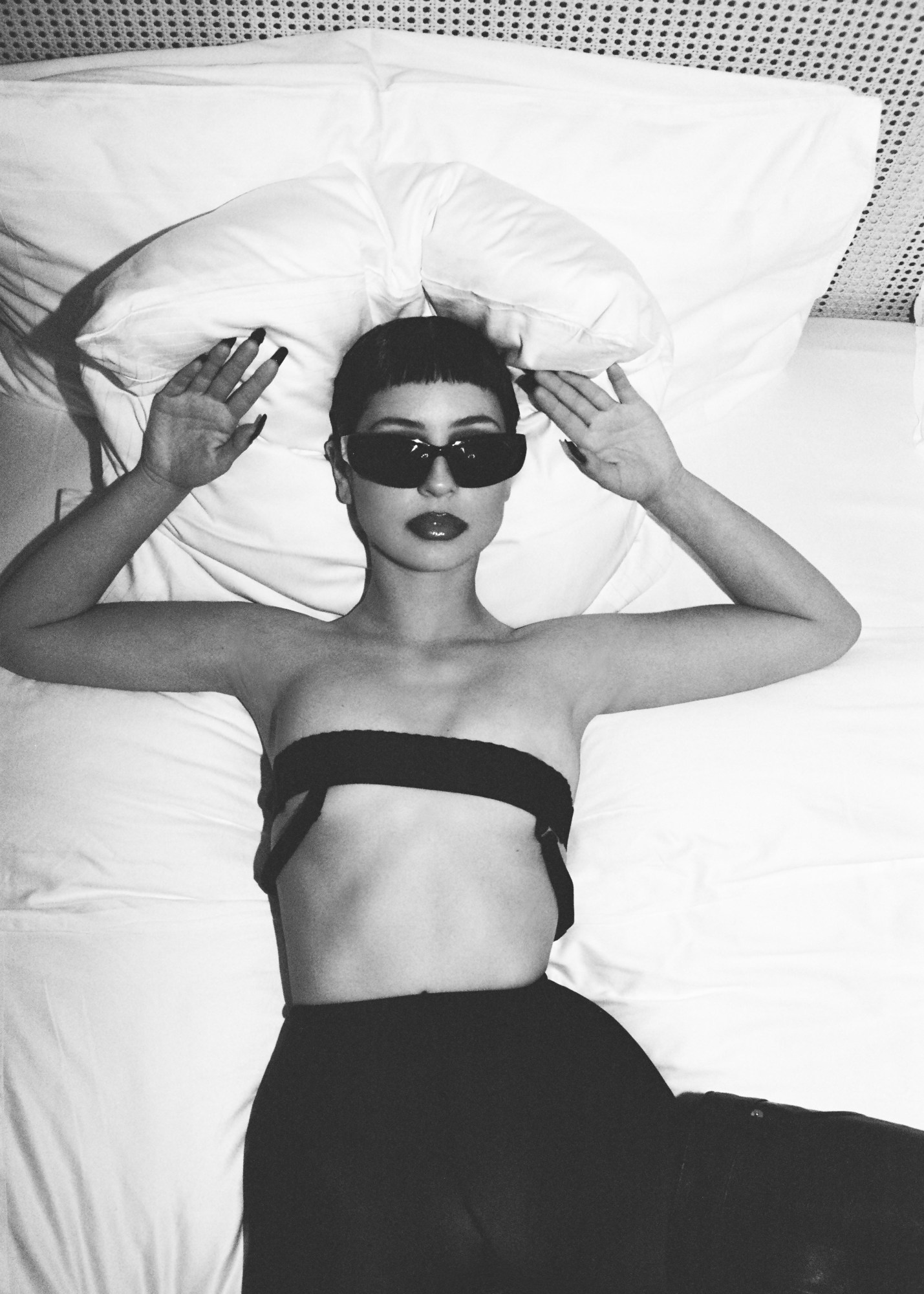 the resulting photo, of Alexa Demie laying on her bed with sunglasses on and a thin bandeau top covering her breasts, taken from above