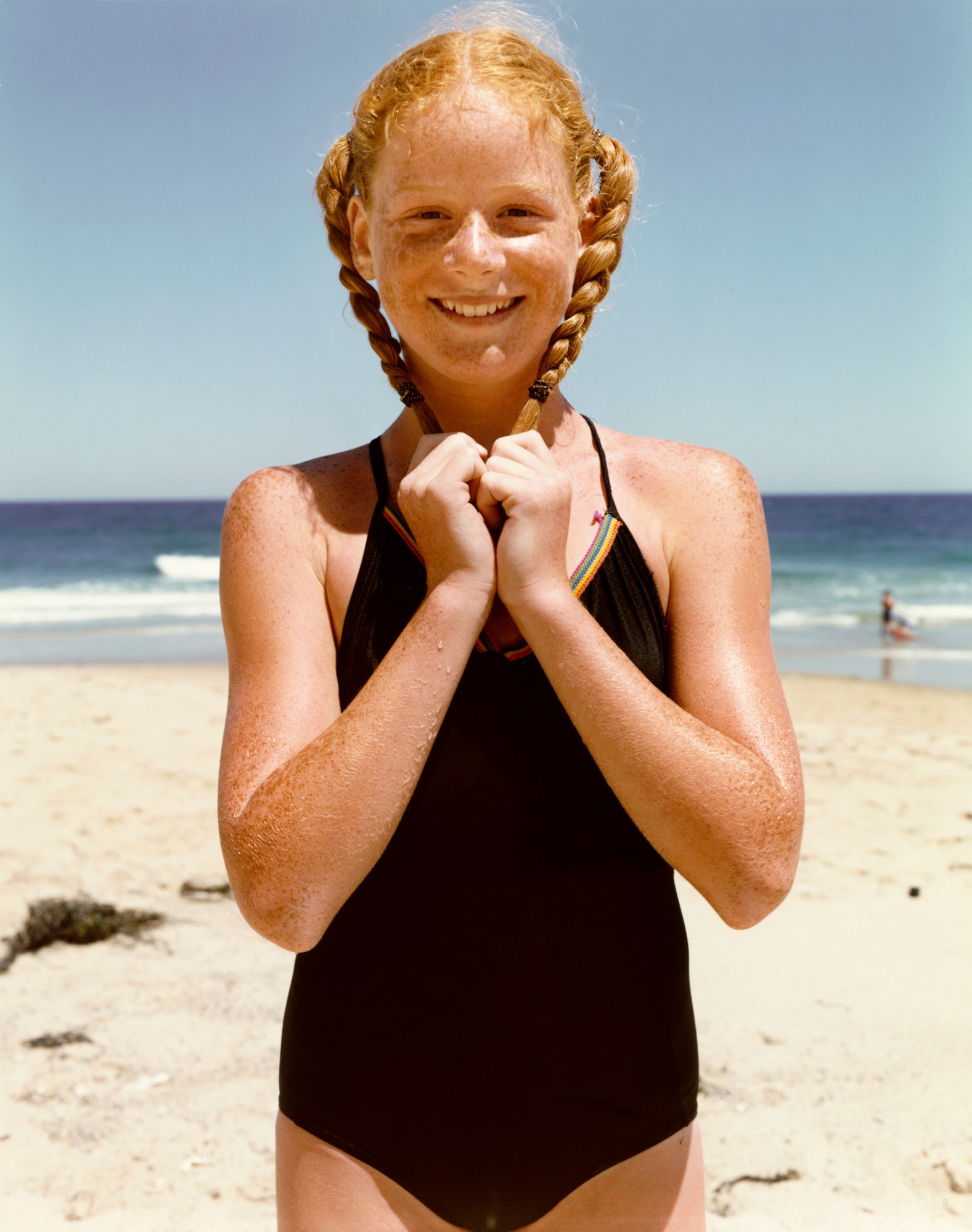 portrait of a young redheaded model with two braids in a black swimsuit