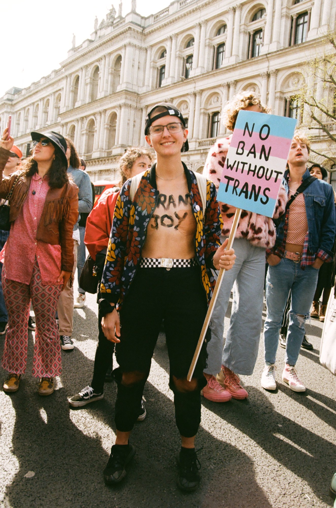 Protester with 'trans joy' written on their chest and a sign saying 'no ban without trans' at the ban trans conversion therapy protest at Downing Street, London.