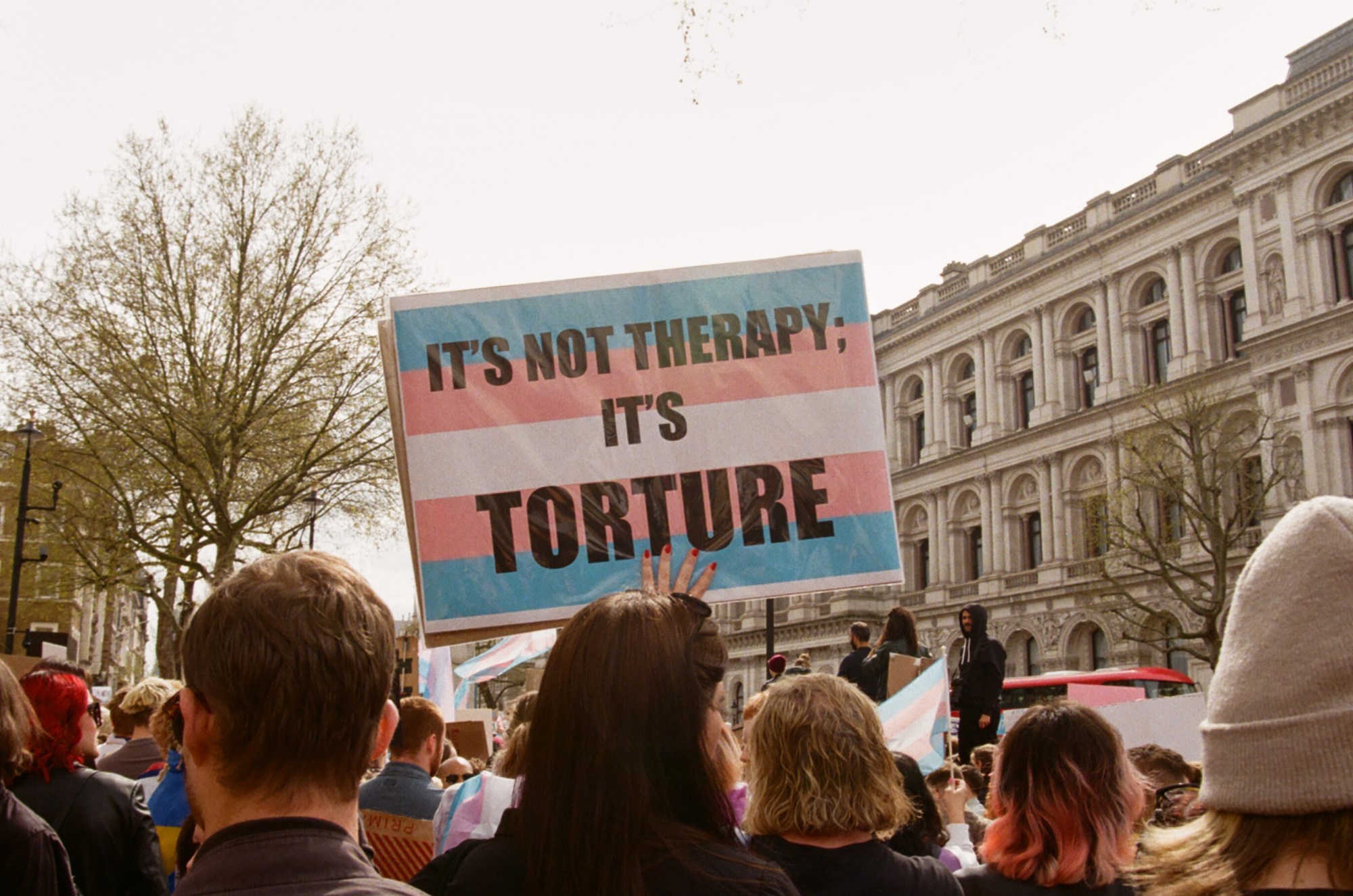 Protesters with sign saying 'It's not therapy; it's torture' at the ban trans conversion therapy protest at Downing Street, London.