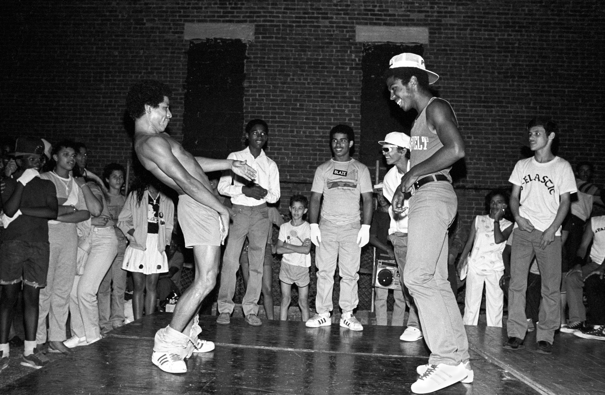 a crowd surrounds two men facing off in a rap battle