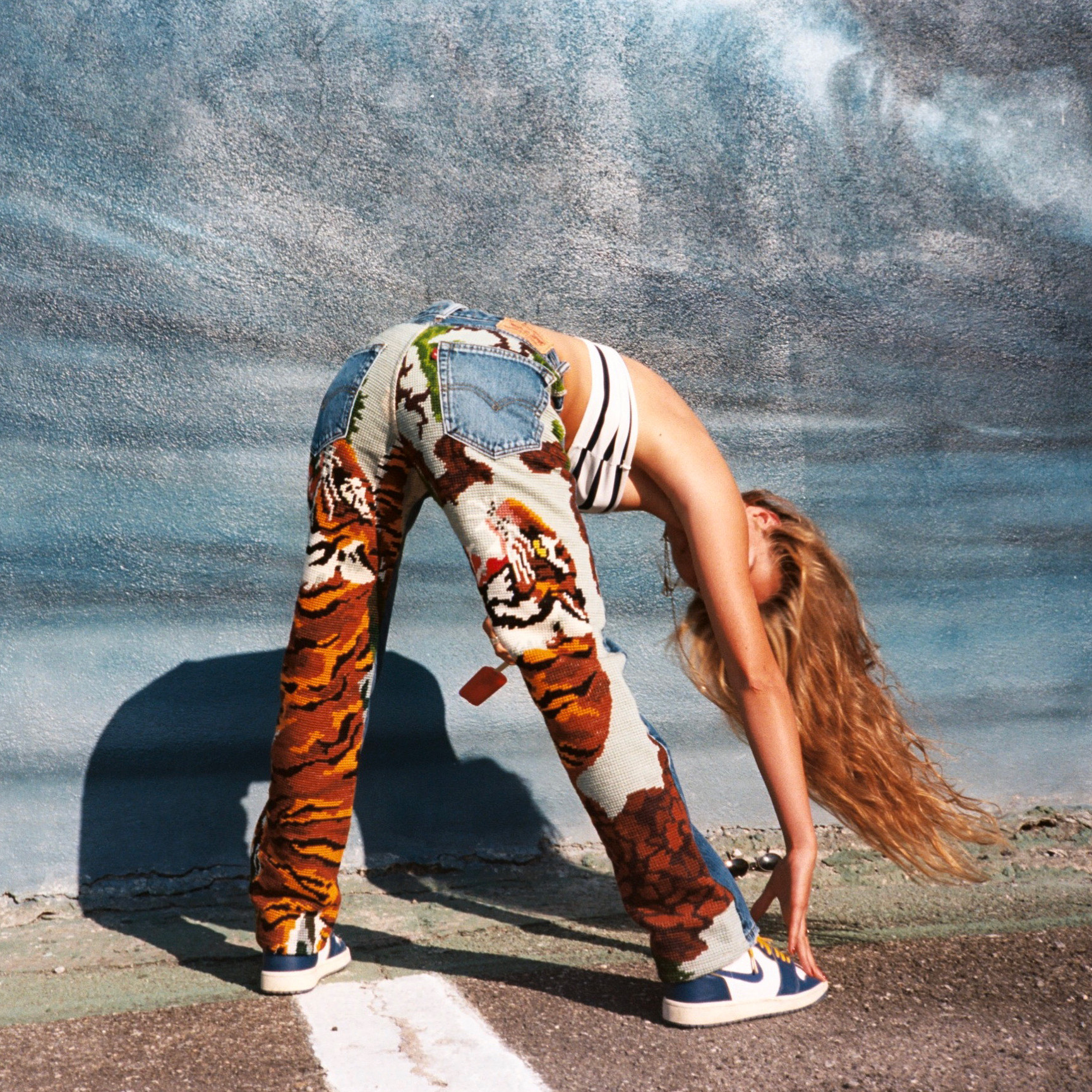 a model bending over in embroidered jeans by siam circle