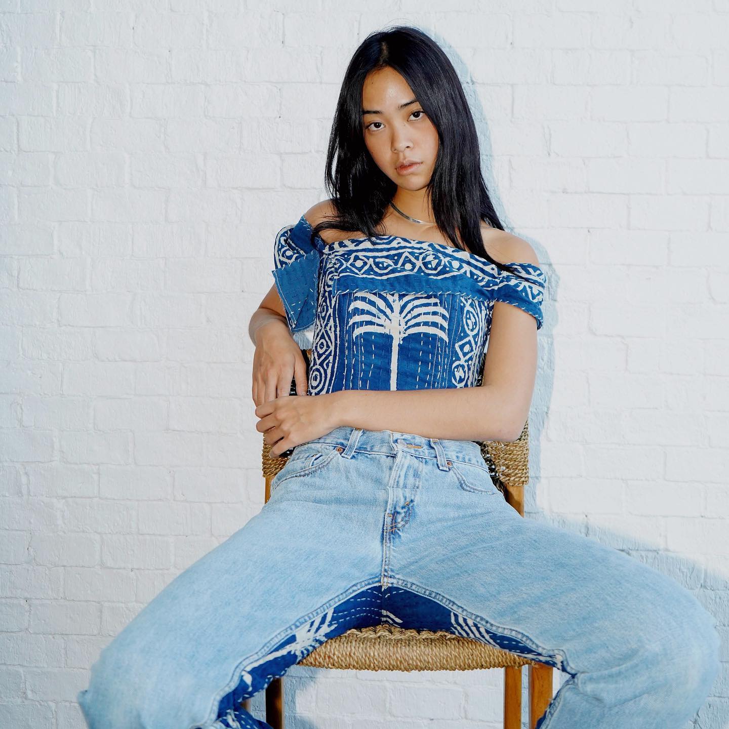 a model sitting on a chair wearing an upcycled corset and jeans by siam circle