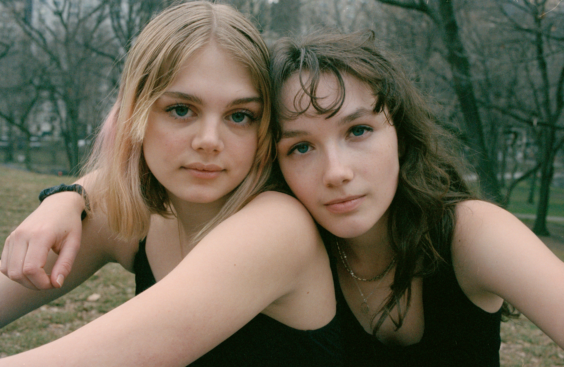 two girls in a park in black tank tops look into the camera