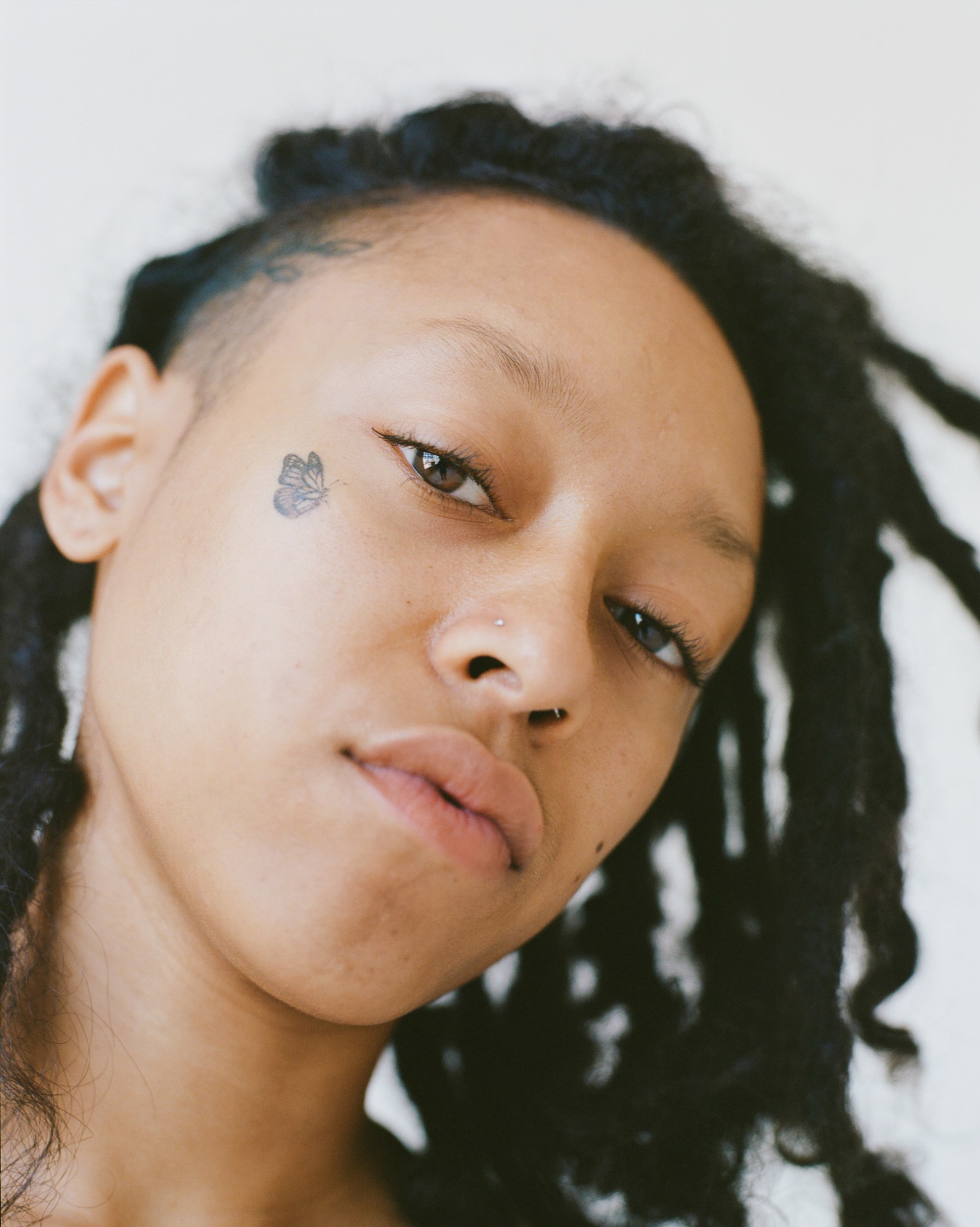 facial close up of a model with a butterfly cheek tattoo