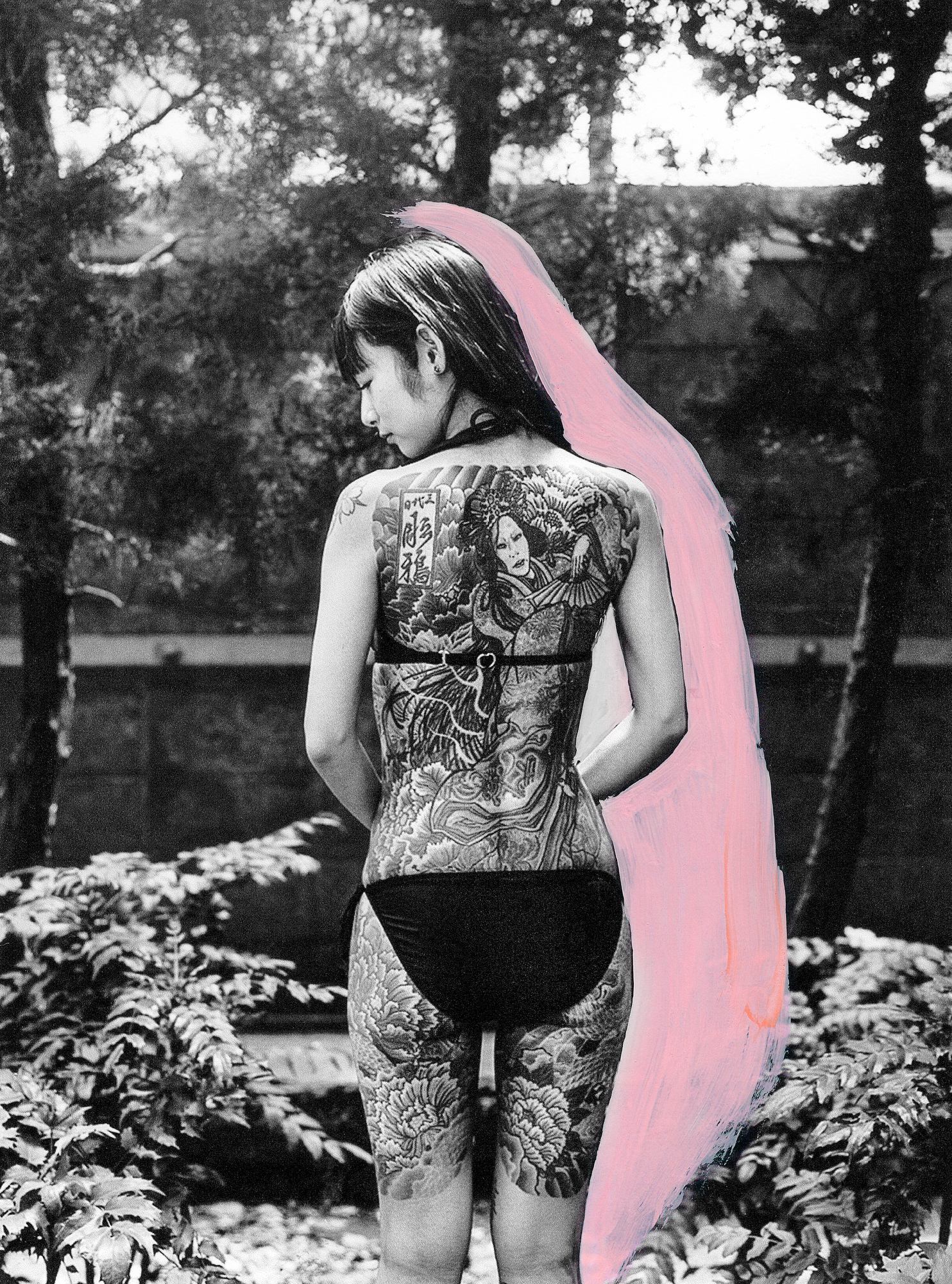 a tattooed yakuza woman looking to her left in black-and-white with a pink streak outlining her body