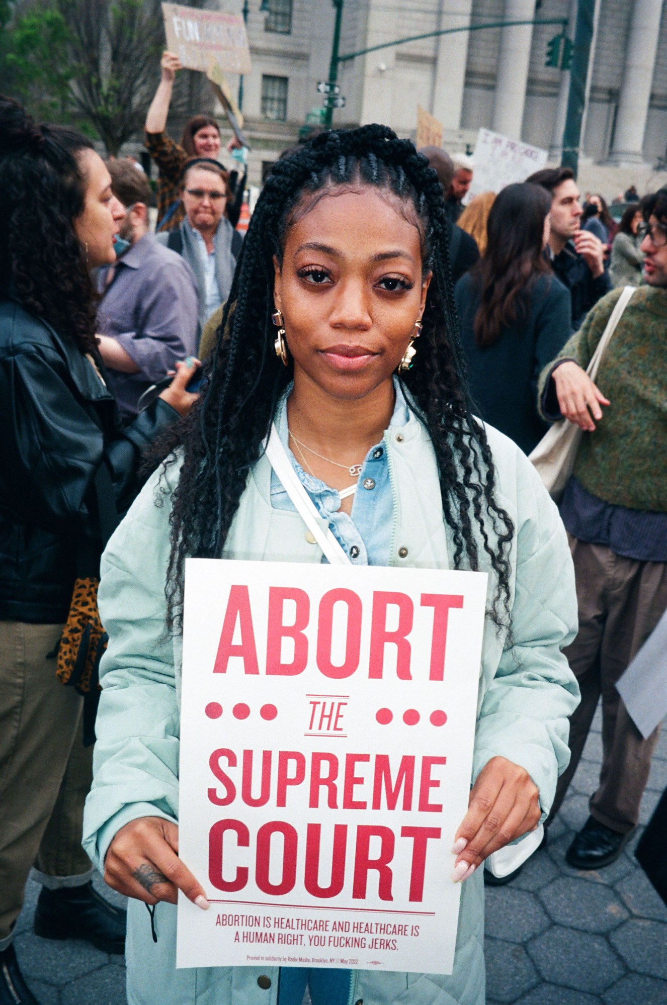 a protestor in new york holding a sign that reads abort the supreme court