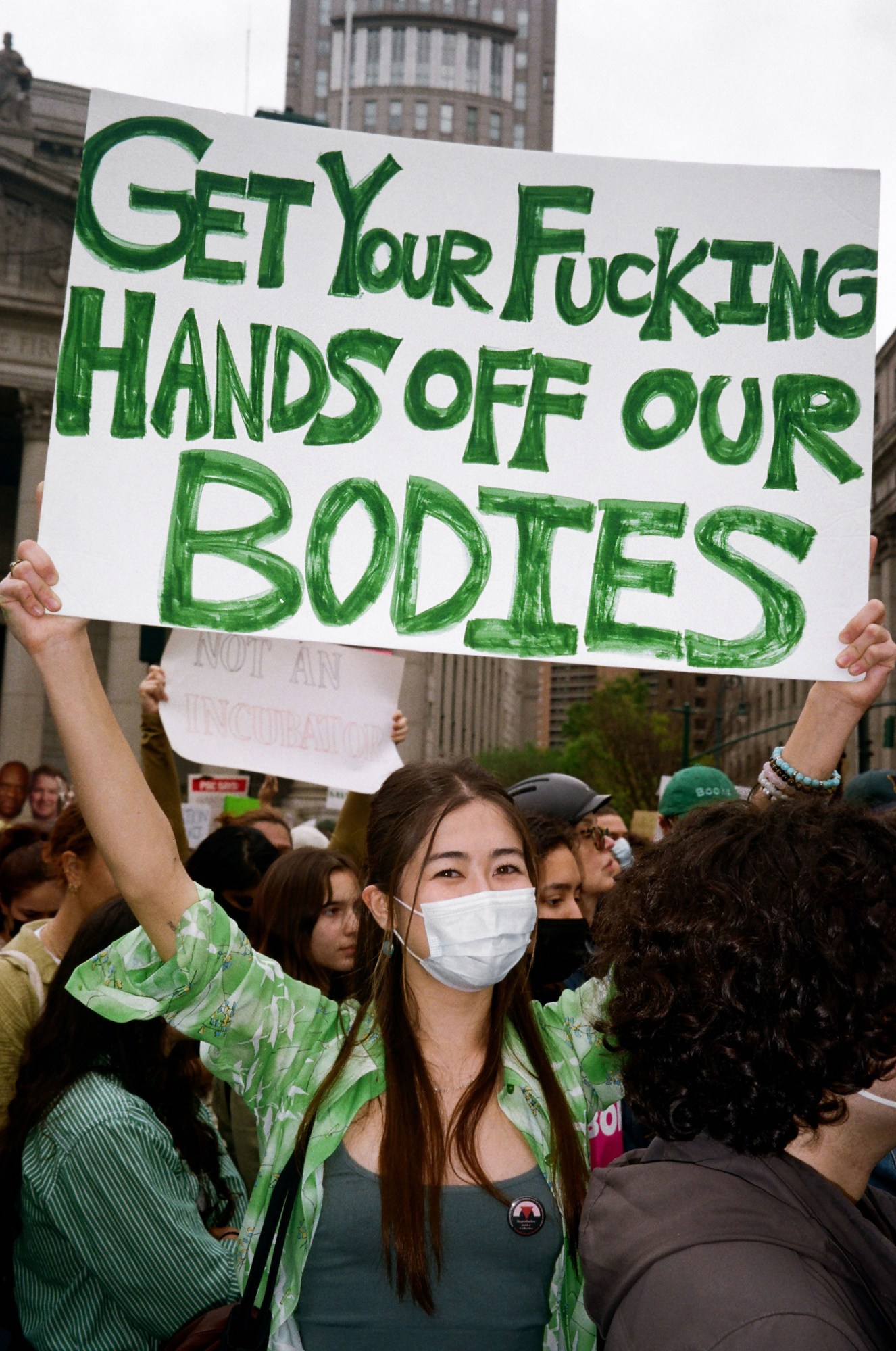 a protestor in nyc holding a sign that reads get your fucking hands off our bodies