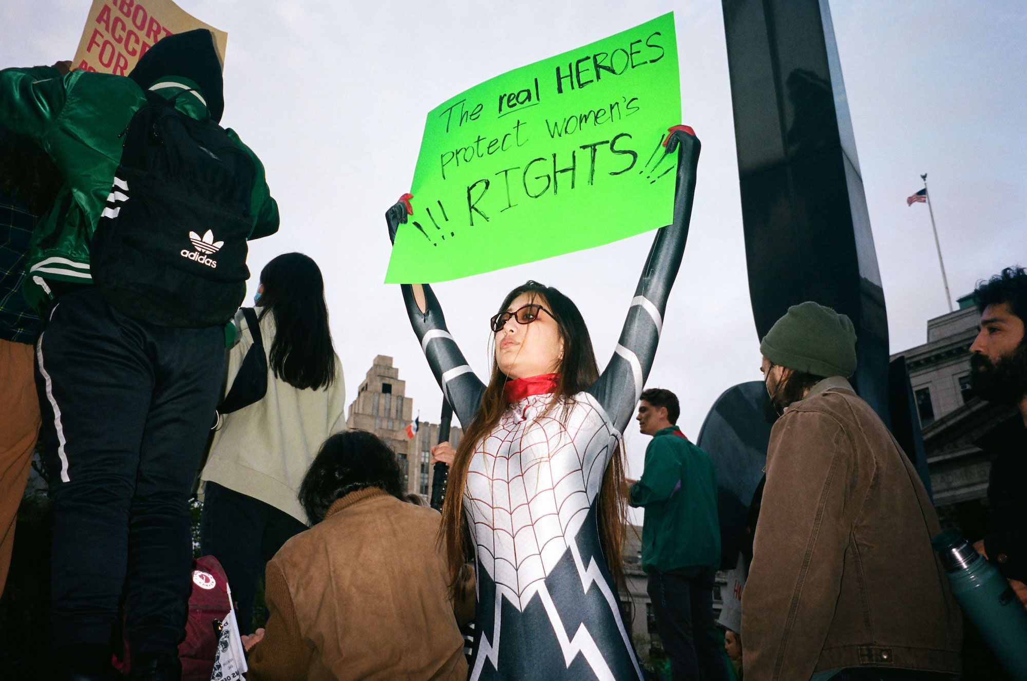 an abortion rights protestor holding a sign in a spiderman suit