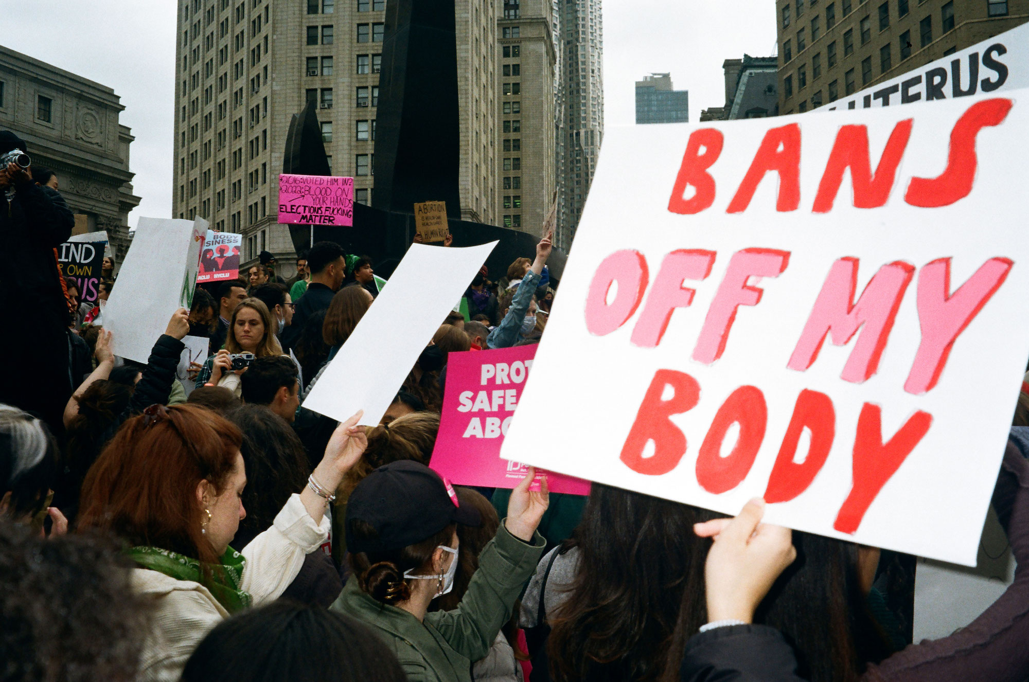 a sea of protestors in new york and a sign that reads bans off my body