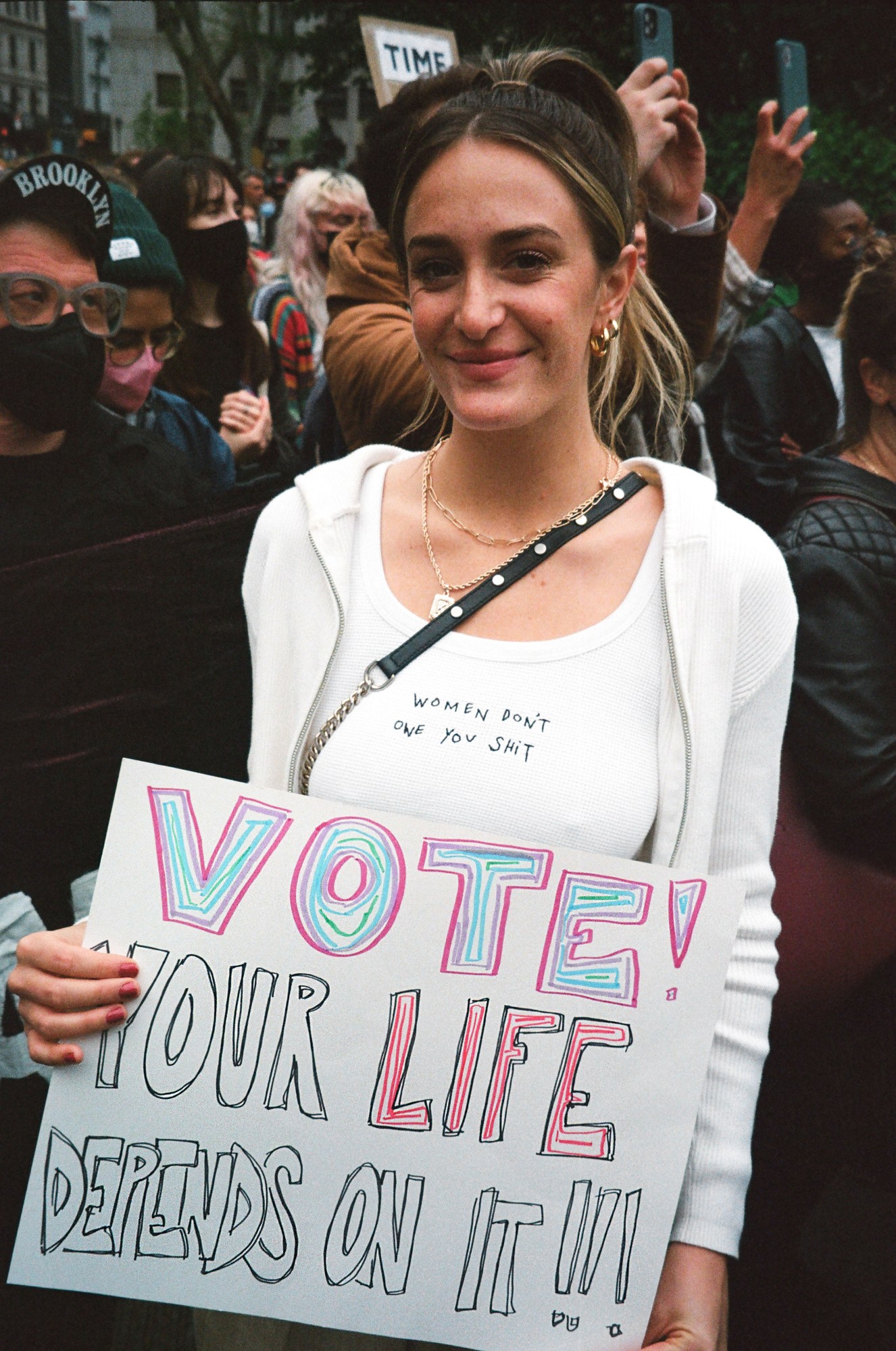 a protestor in new york holding a sign that reads vote your life depends on it