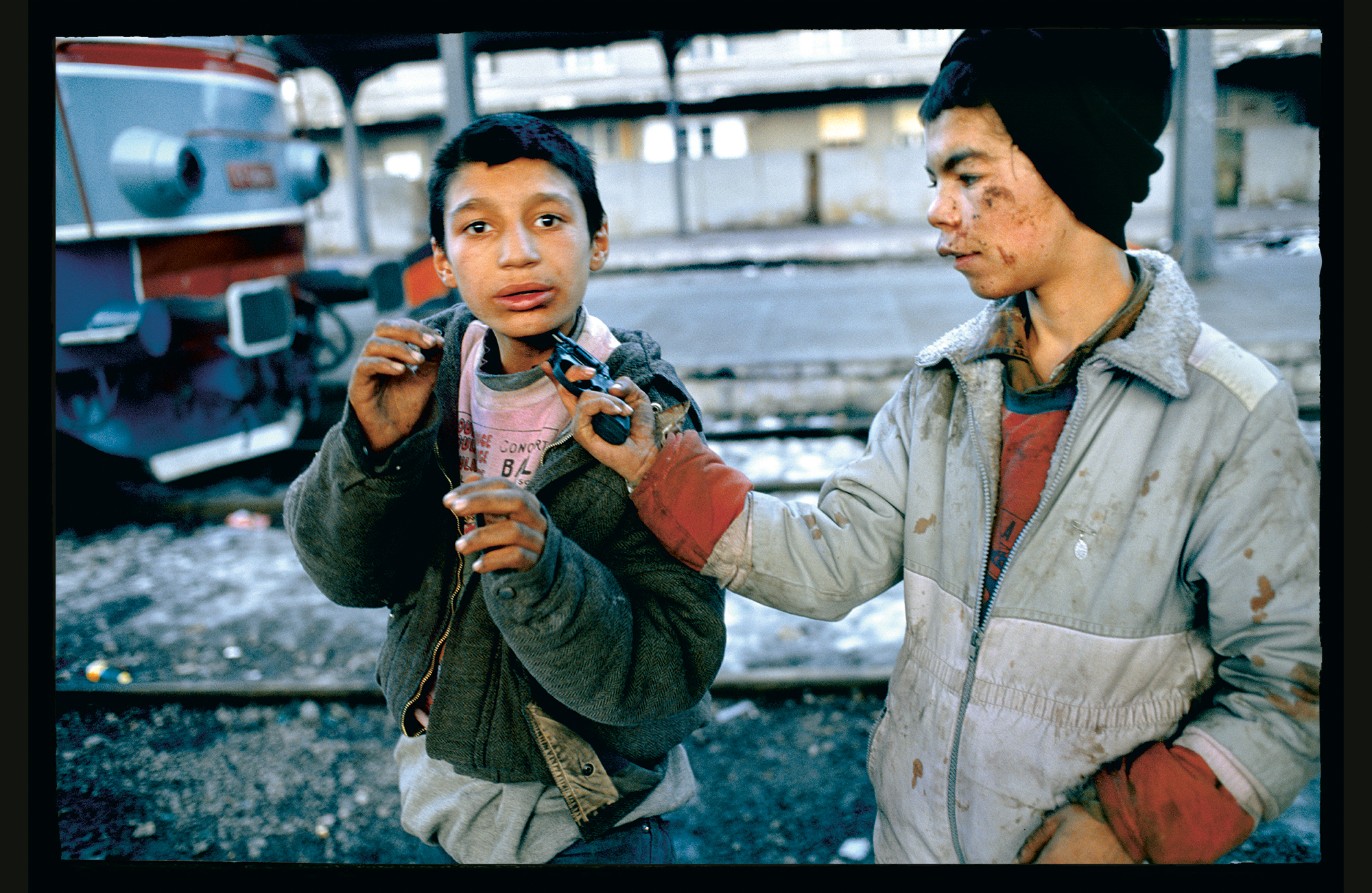 Two young boys playing with a toy gun.