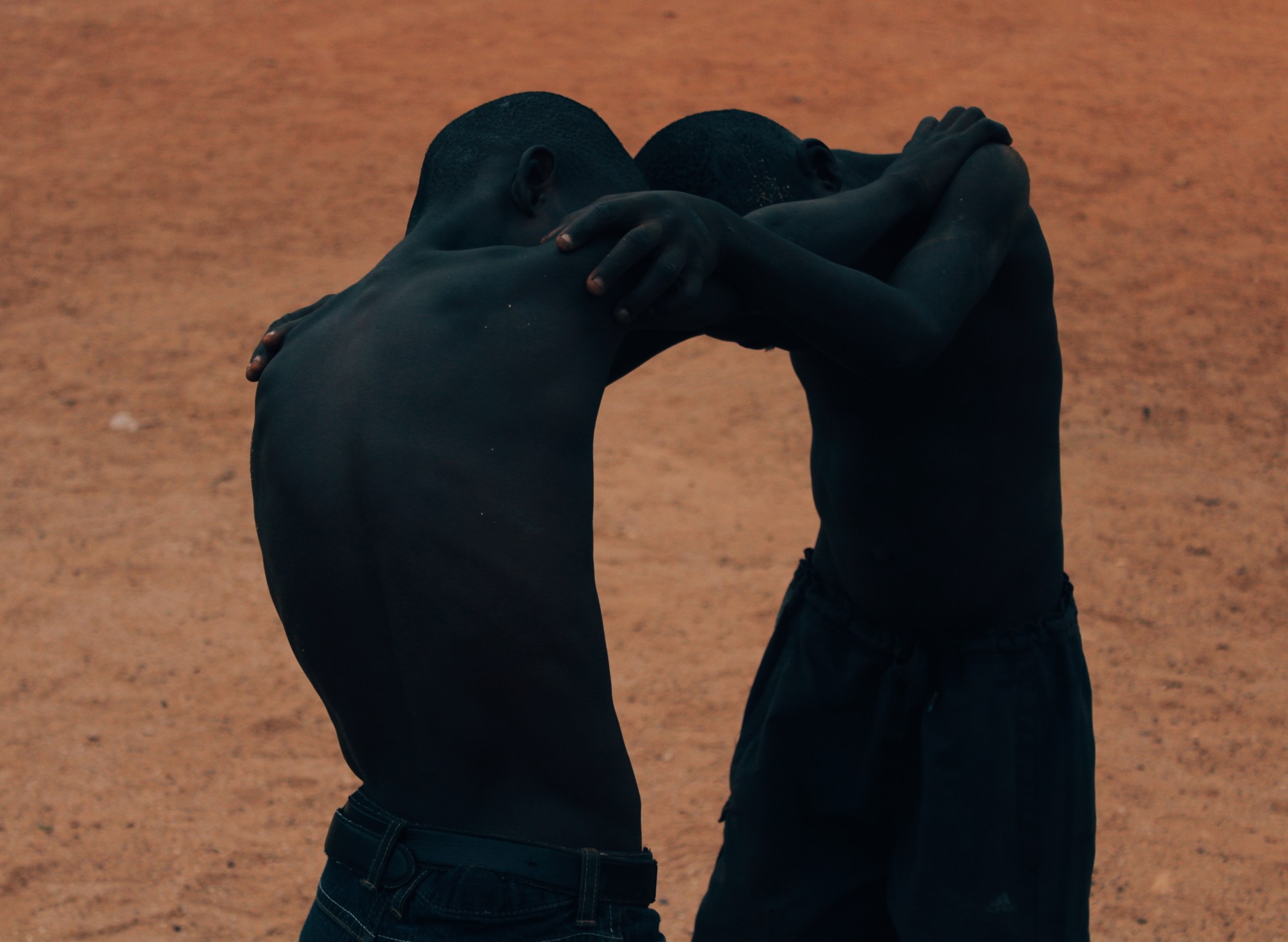 Two boys playing in a dusty orange field.