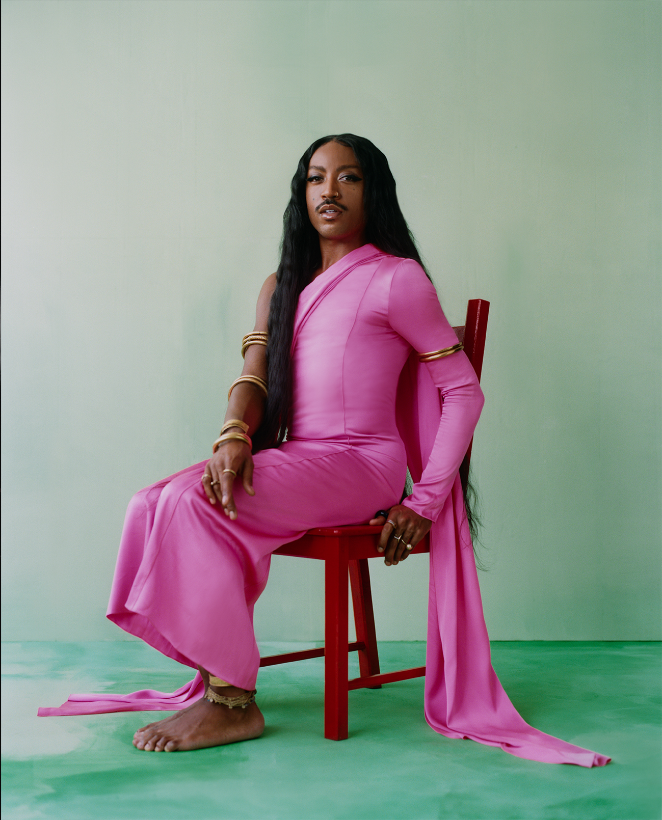 portrait of LaBelleza in a pink dress against a green background for Camila Falquez: Gods That Walk Amongst Us